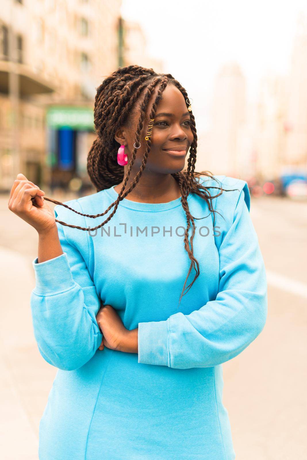 Pretty young black woman smiling in the middle of the city. Selective focus.