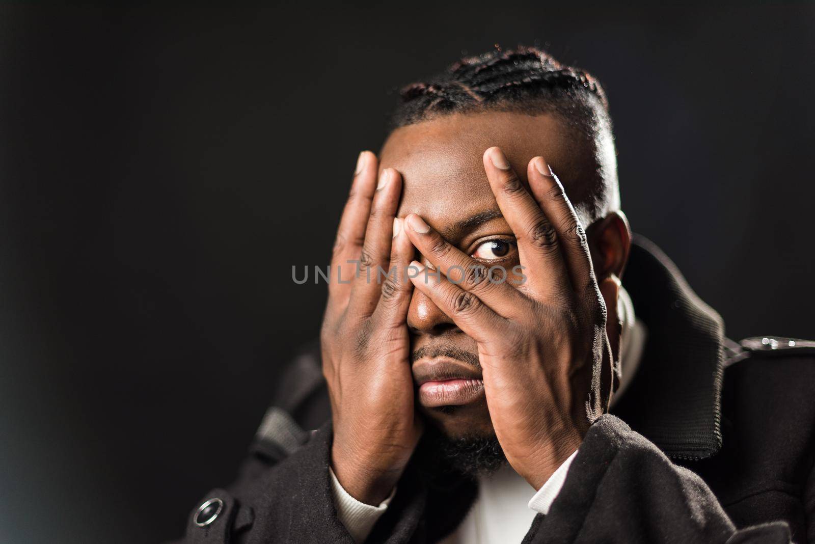 Scared black man covering his face with his hands. by ivanmoreno