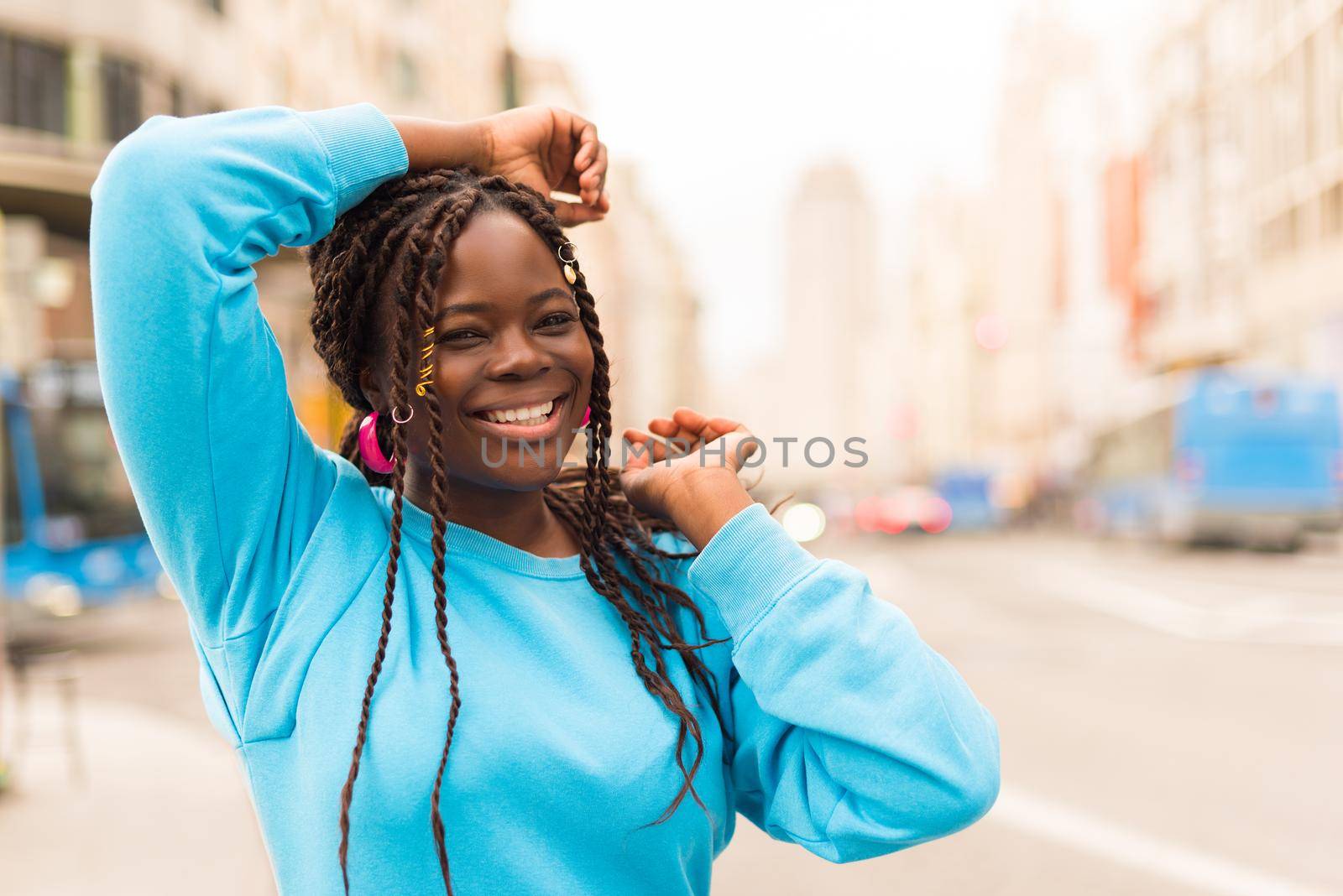 Pretty young black woman in the middle of the city, smiling at camera. Selective focus.