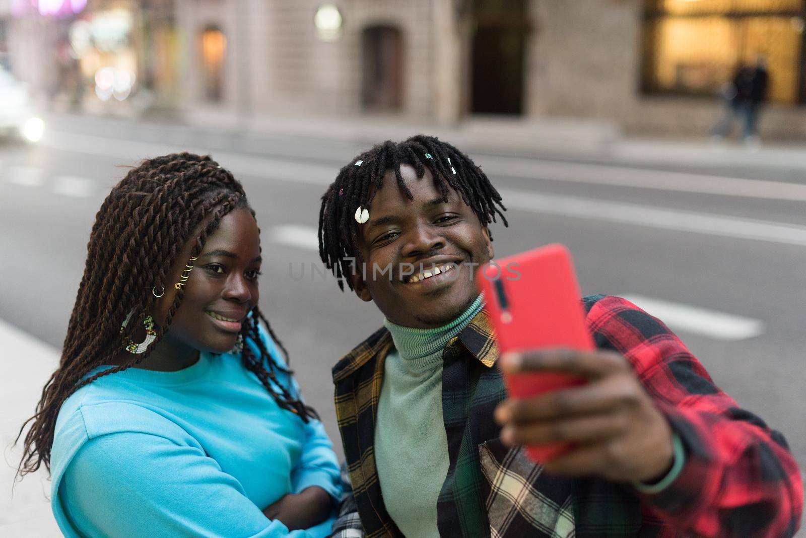 Smiling black couple taking a selfie on the street. Selective focus.