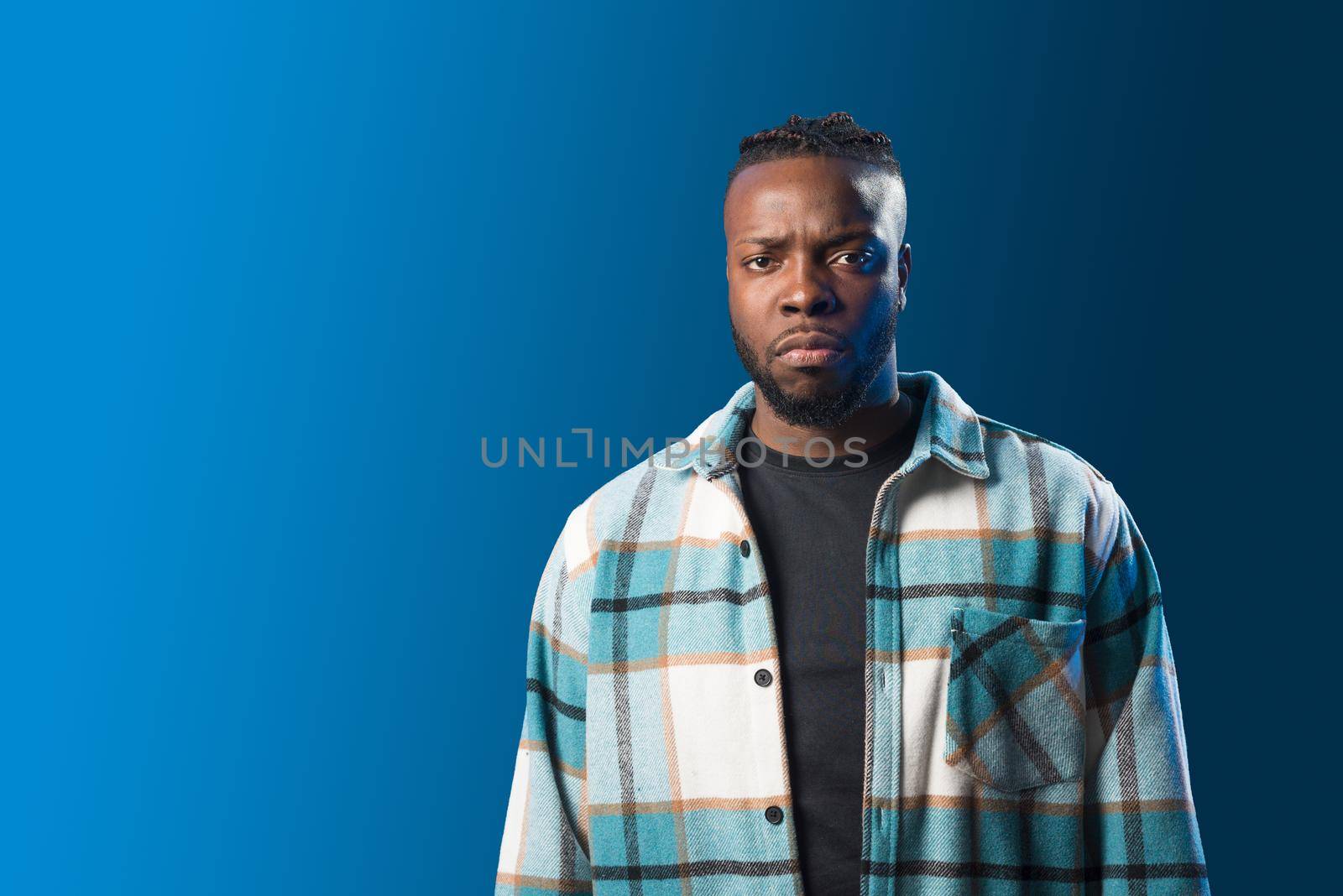 Handsome black man, serious and angry. Blue background. by ivanmoreno