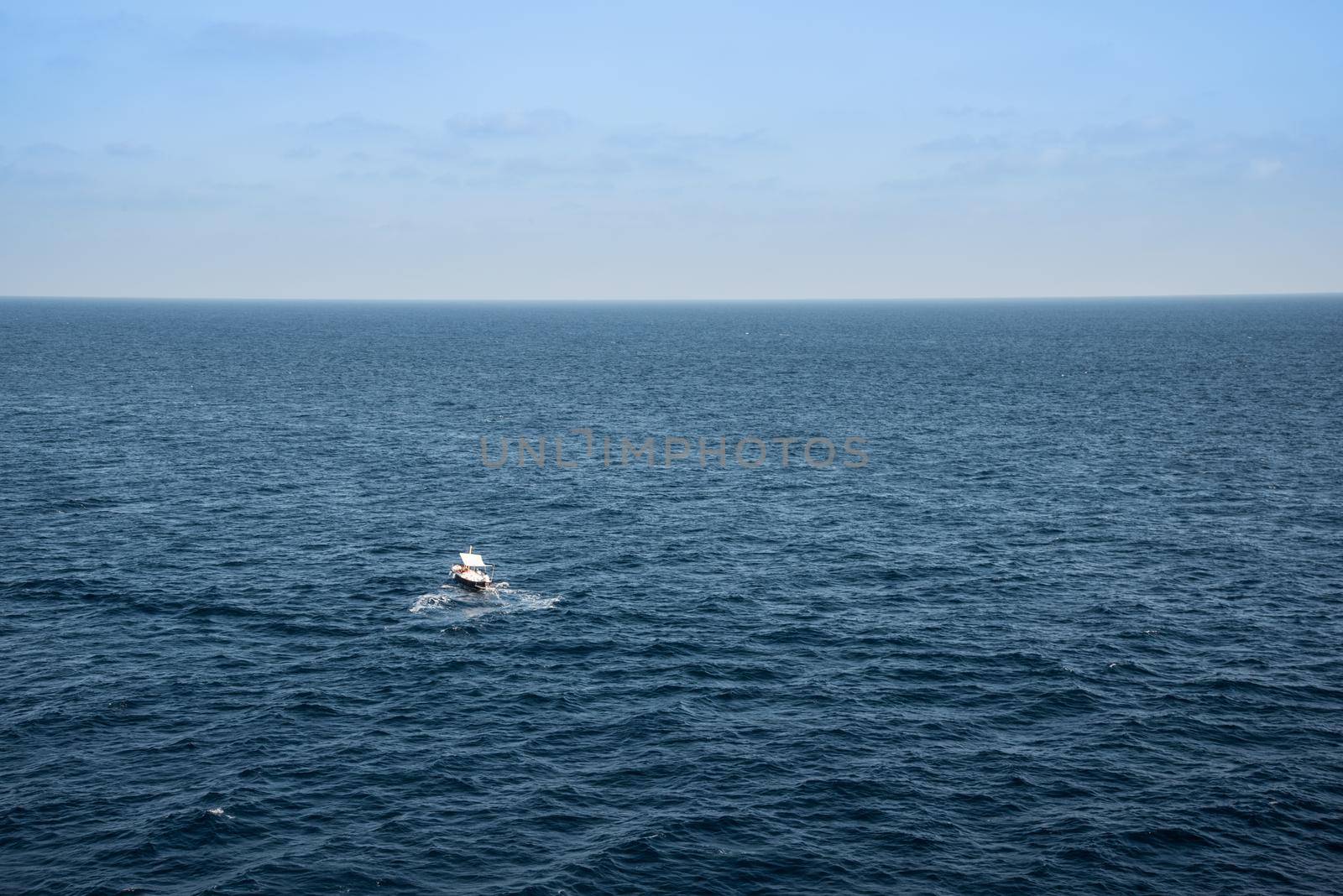 Small boat in the middle of a huge sea on a sunny summer day.