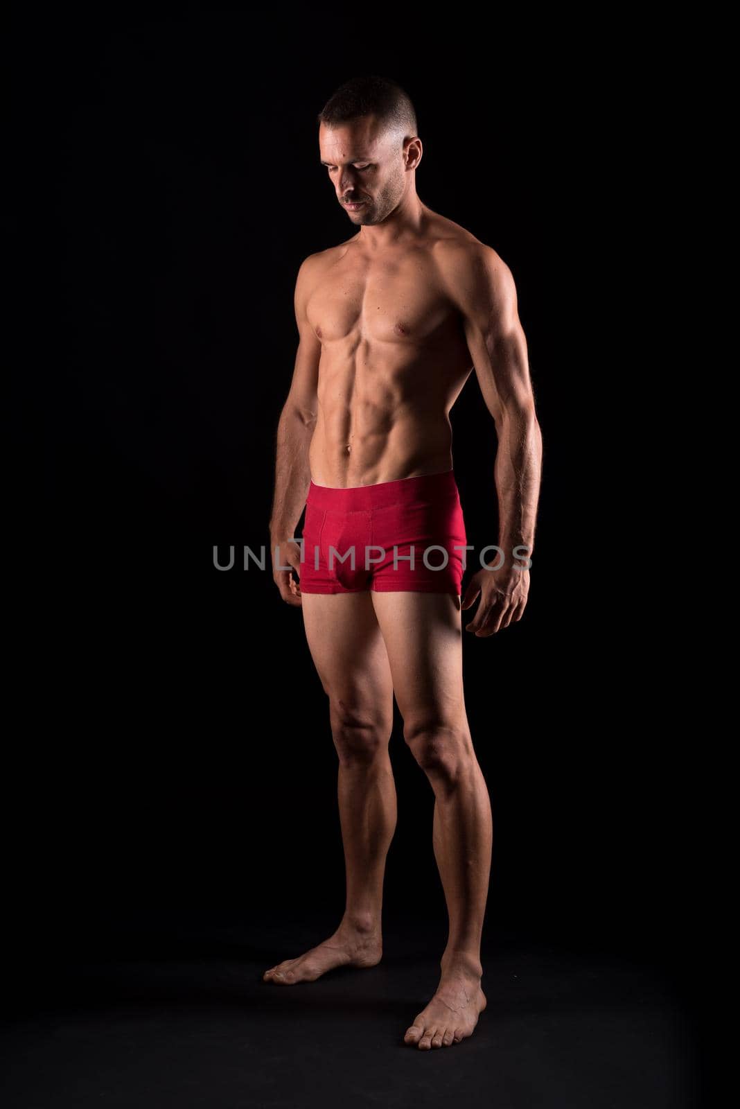 Athletic man in underwear. Full body. Black background.