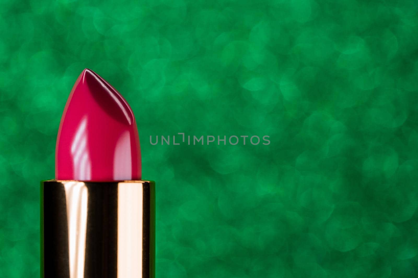 Pink lipstick rising out from container on shiny green background. Showcase or advertisement for beauty brand, Concept of fashion, cosmetics with copy space. High quality