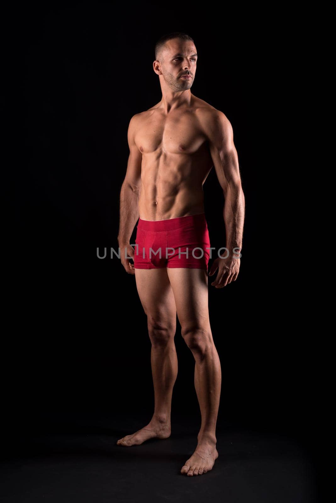 Athletic man in underwear. Full body. Black background.
