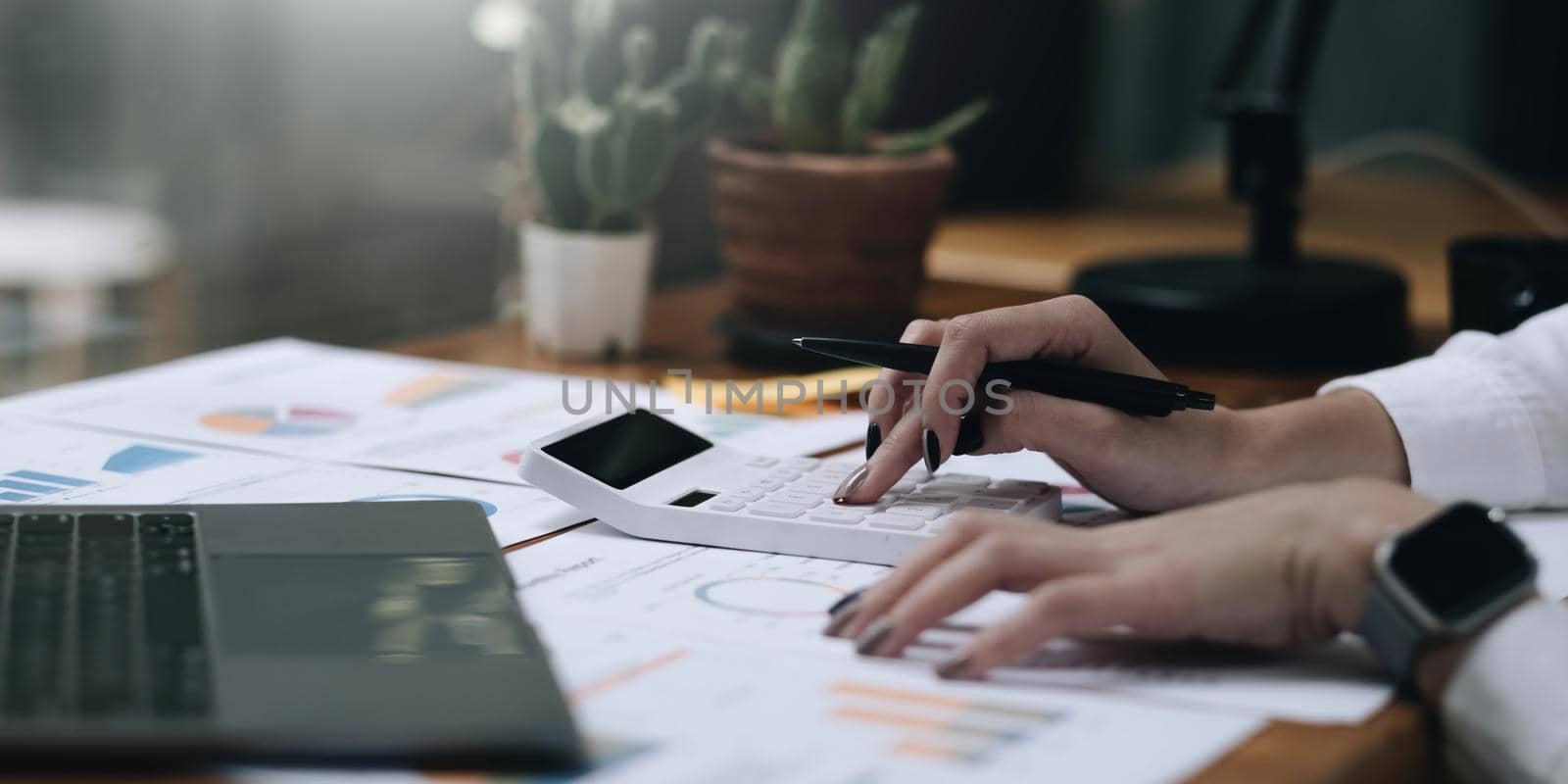 Close up Business woman using calculator and laptop for do math finance on wooden desk in office and business working background, tax, accounting, statistics and analytic research concept.