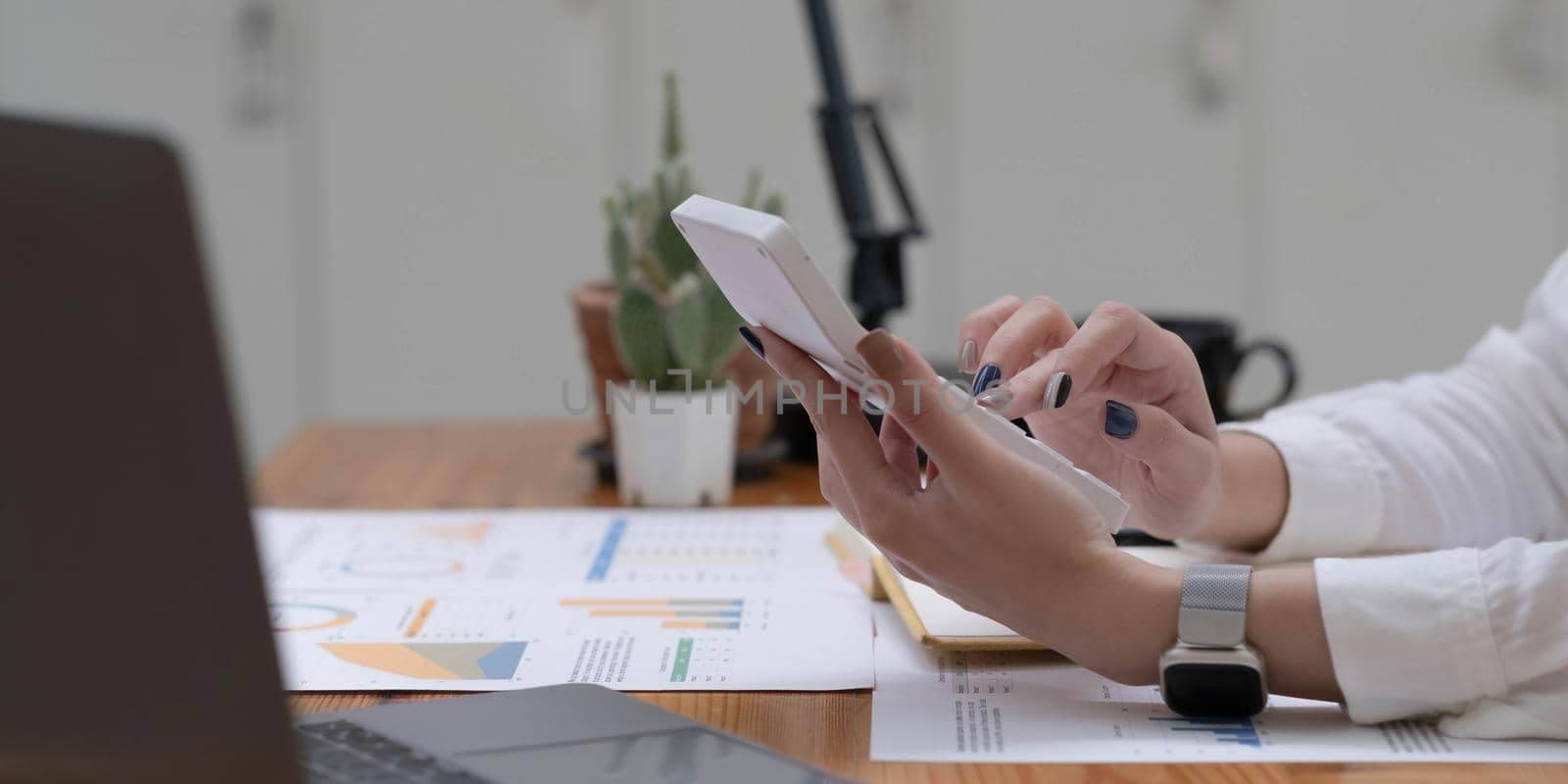 Close up Business woman using calculator and laptop for do math finance on wooden desk in office and business working background, tax, accounting, statistics and analytic research concept.