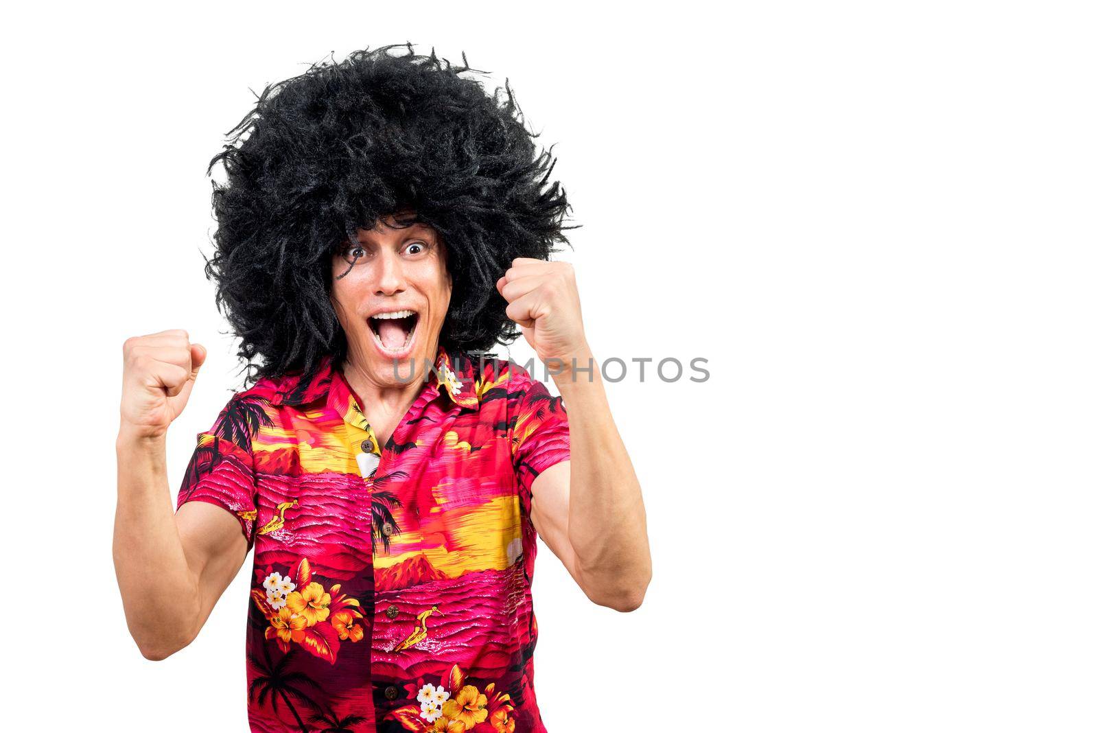 Excited man in vibrant summer shirt and Afro wig clenching fists and yelling while celebrating victory isolated on white background