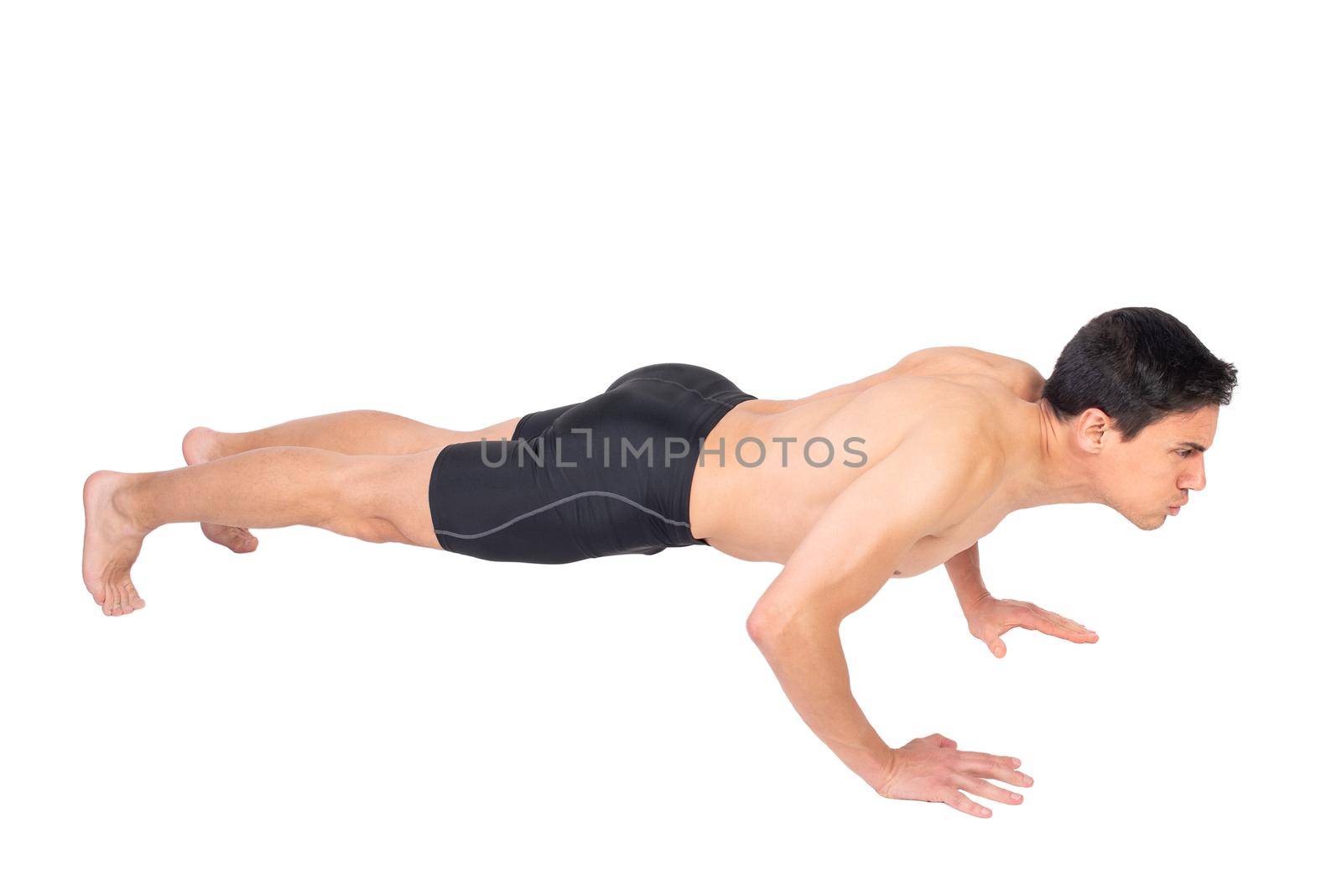 Full body side view of serious sportsman with naked torso performing push ups during fitness workout isolated on white background