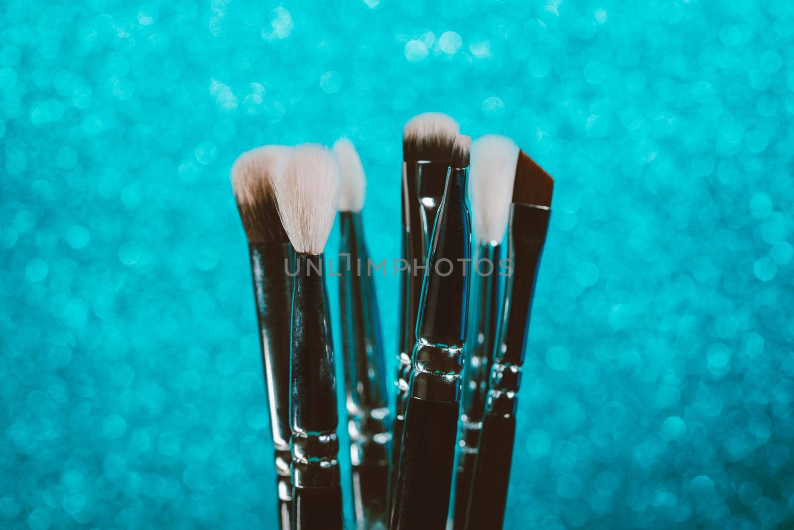 Cosmetics make-up brushes on blue sparkling background. by kristina_kokhanova