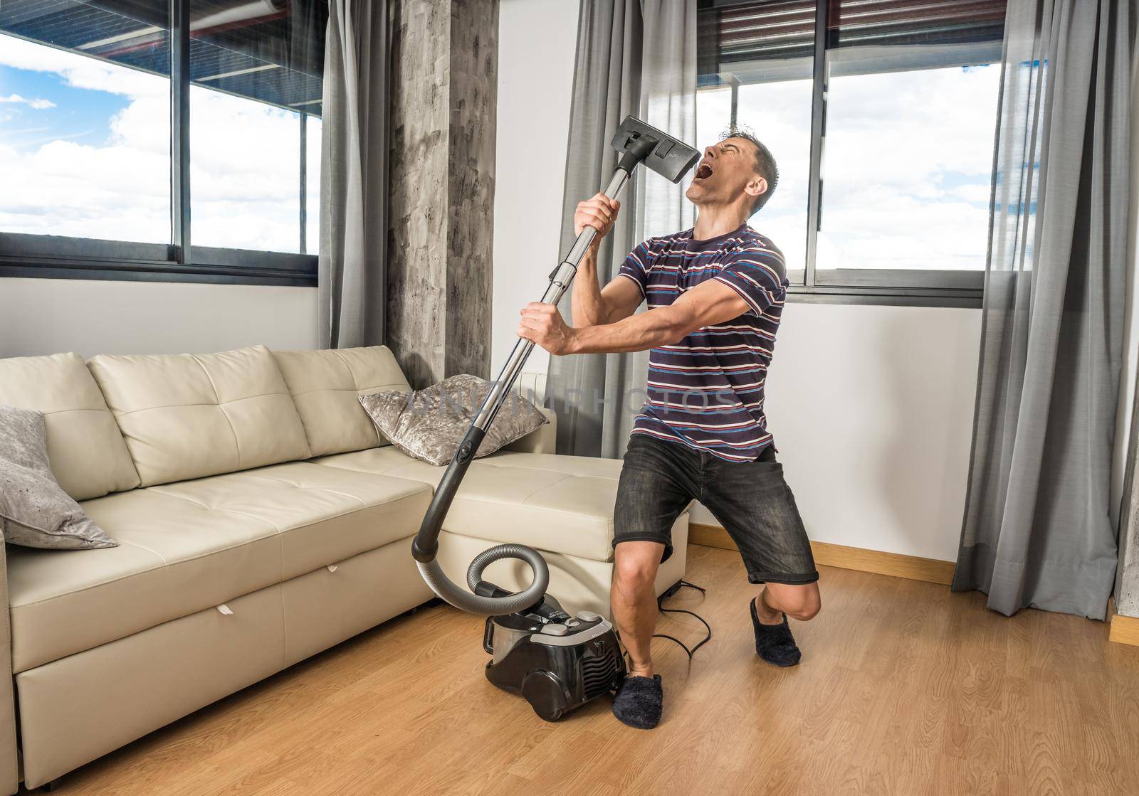 Man singing in the living room of his house holding the vacuum cleaner as if it were a microphone. Full body.