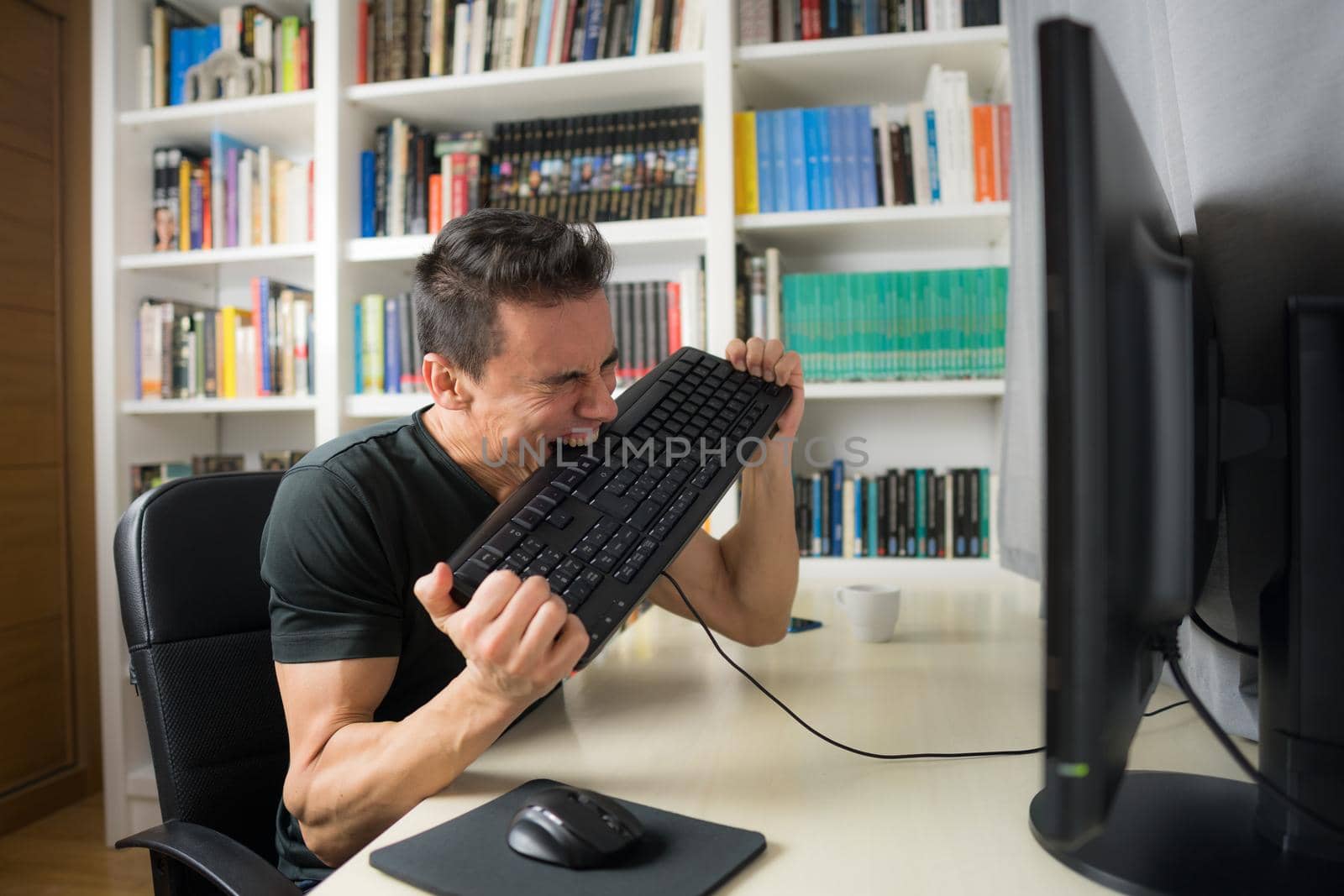 Seated man in a black shirt in front of the computer, hysterical because he does not understand something. Mid shot.