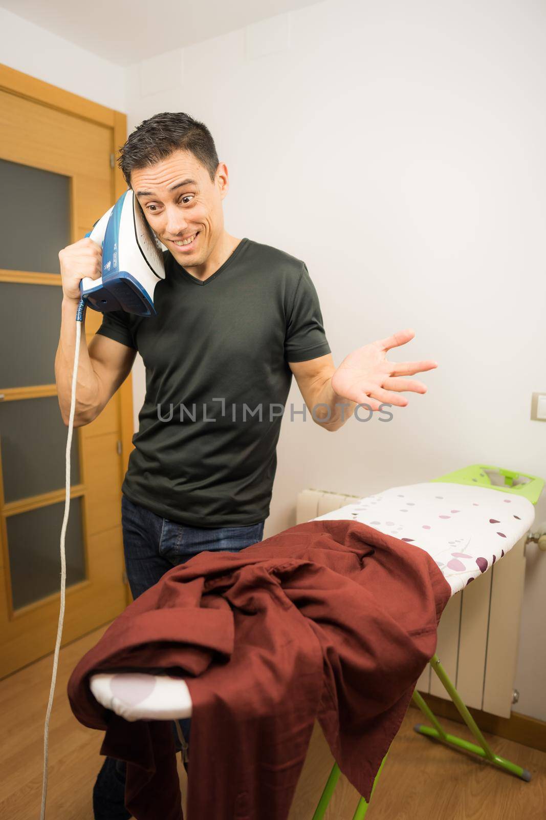 Crazy man talking on the phone with an iron. Mid shot.