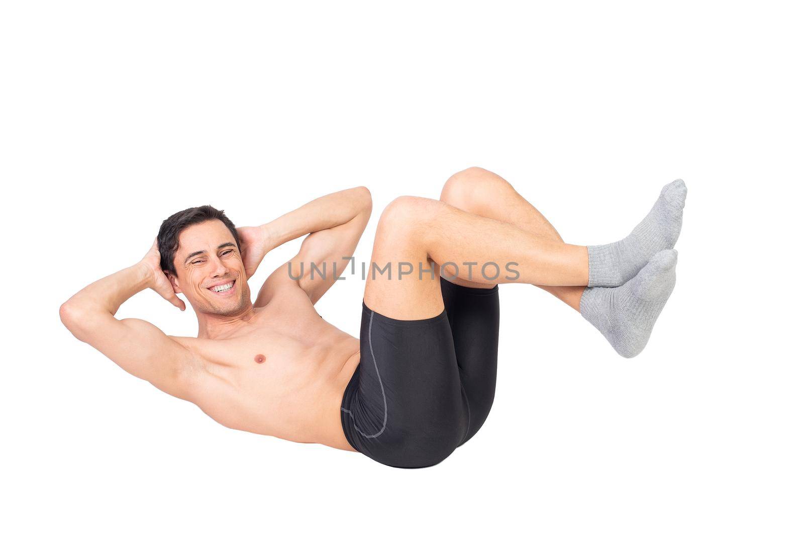 Full body of positive muscular male with naked torso doing abdominal crunches and looking at camera isolated on white background