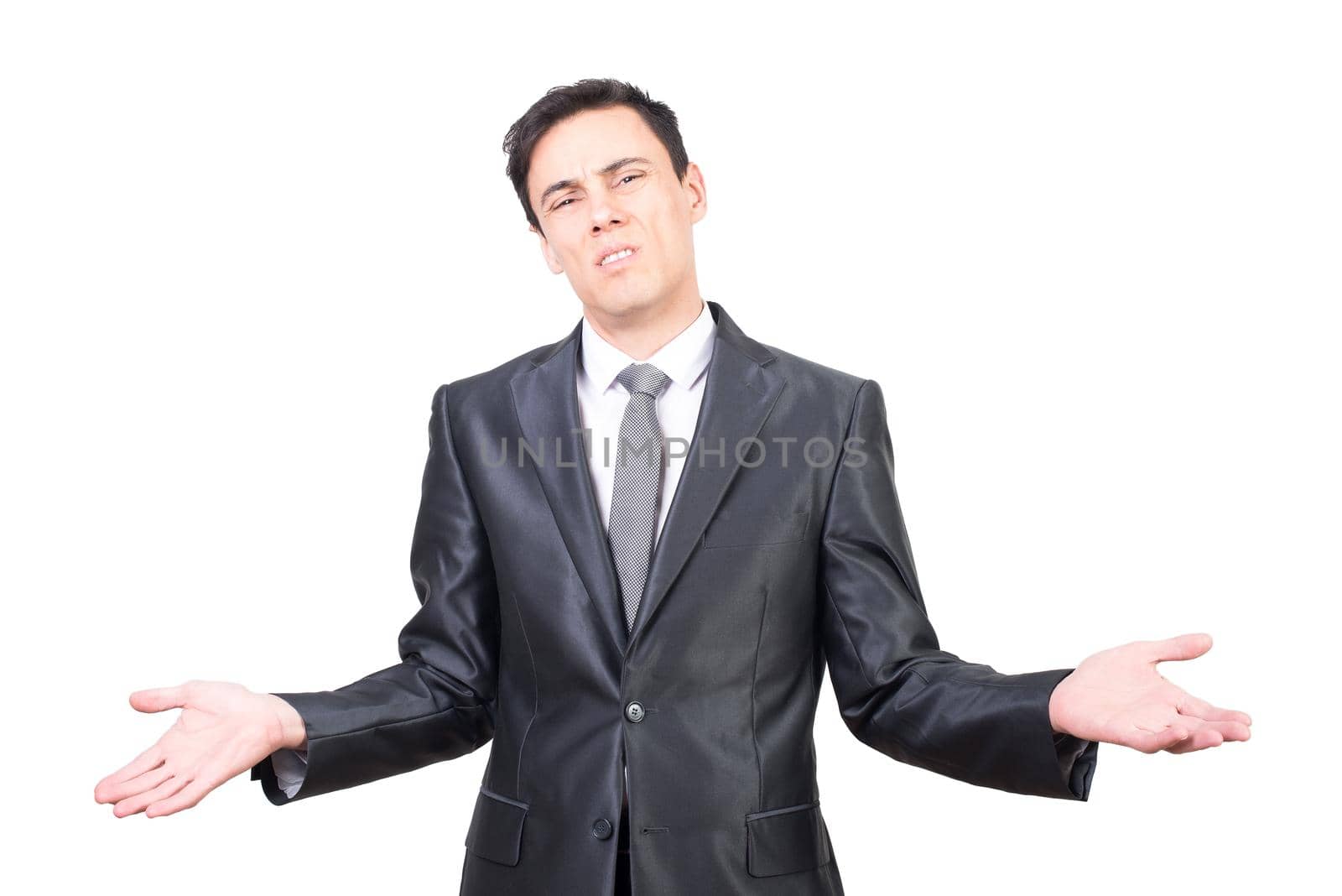 Exhausted young male entrepreneur with dark hair in formal suit and tie shrugging hands and looking at camera while standing against white background after hard working day