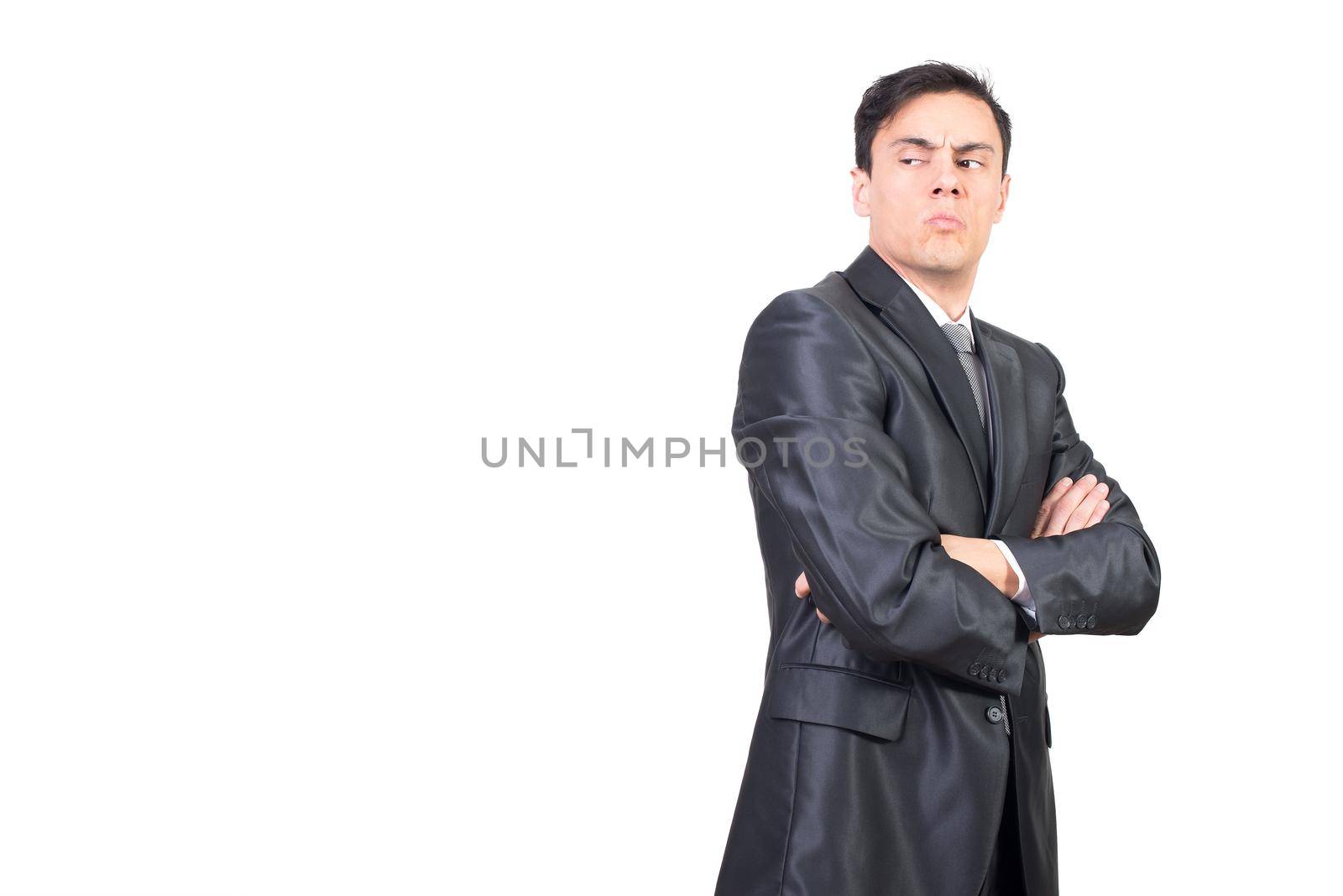 Side view of attentive young male entrepreneur with dark hair in formal outfit looking away with suspicion while standing against white background in studio