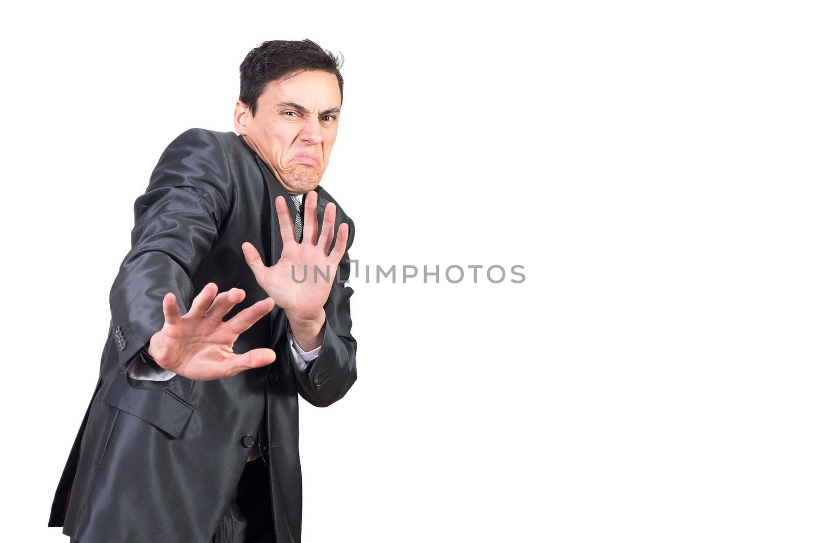 Squeamish young man with dark hair in elegant suit showing stop sign while looking at camera with disgust in face against white background