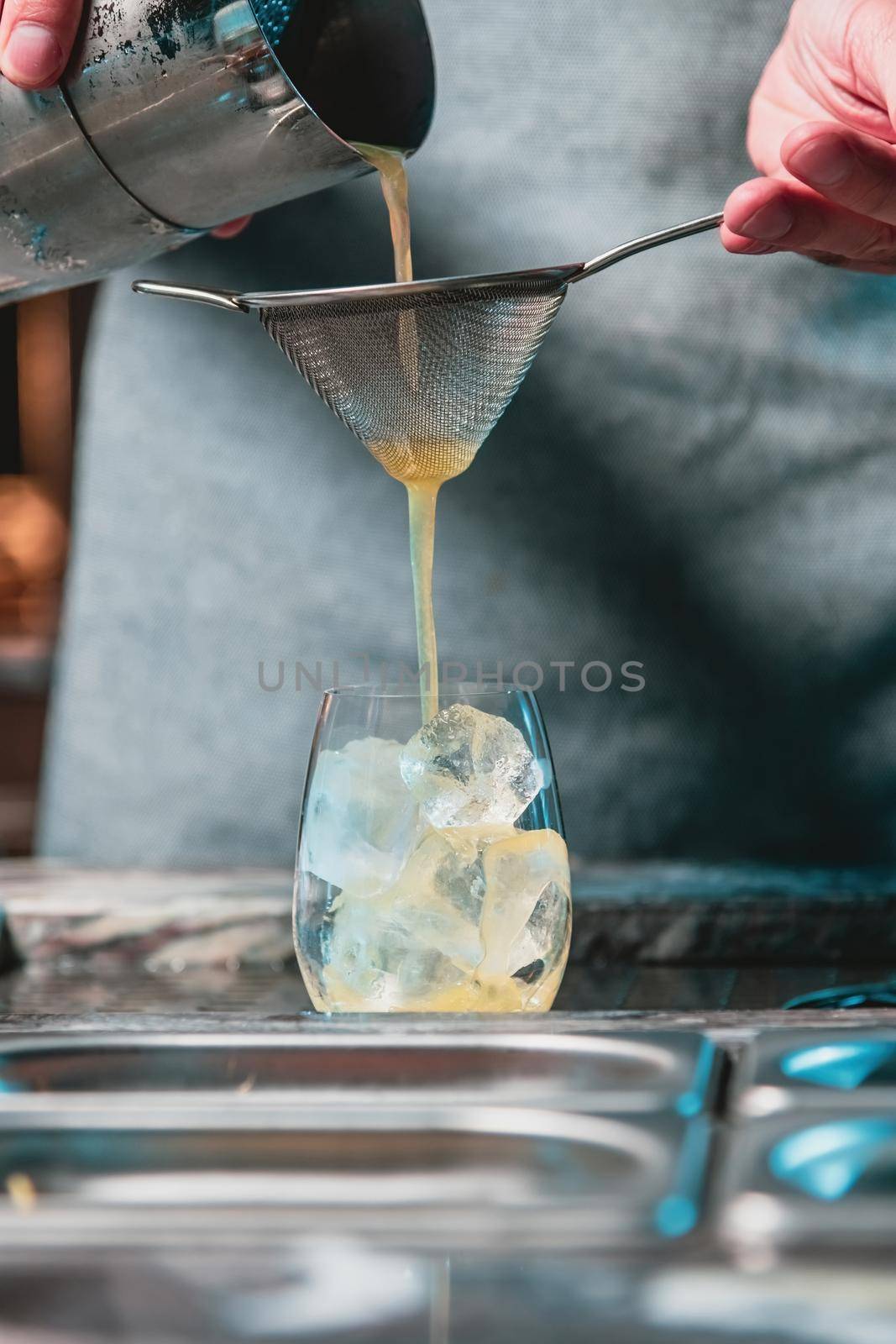 At a luxury nightclub, the bartender strains his cocktail into a glass