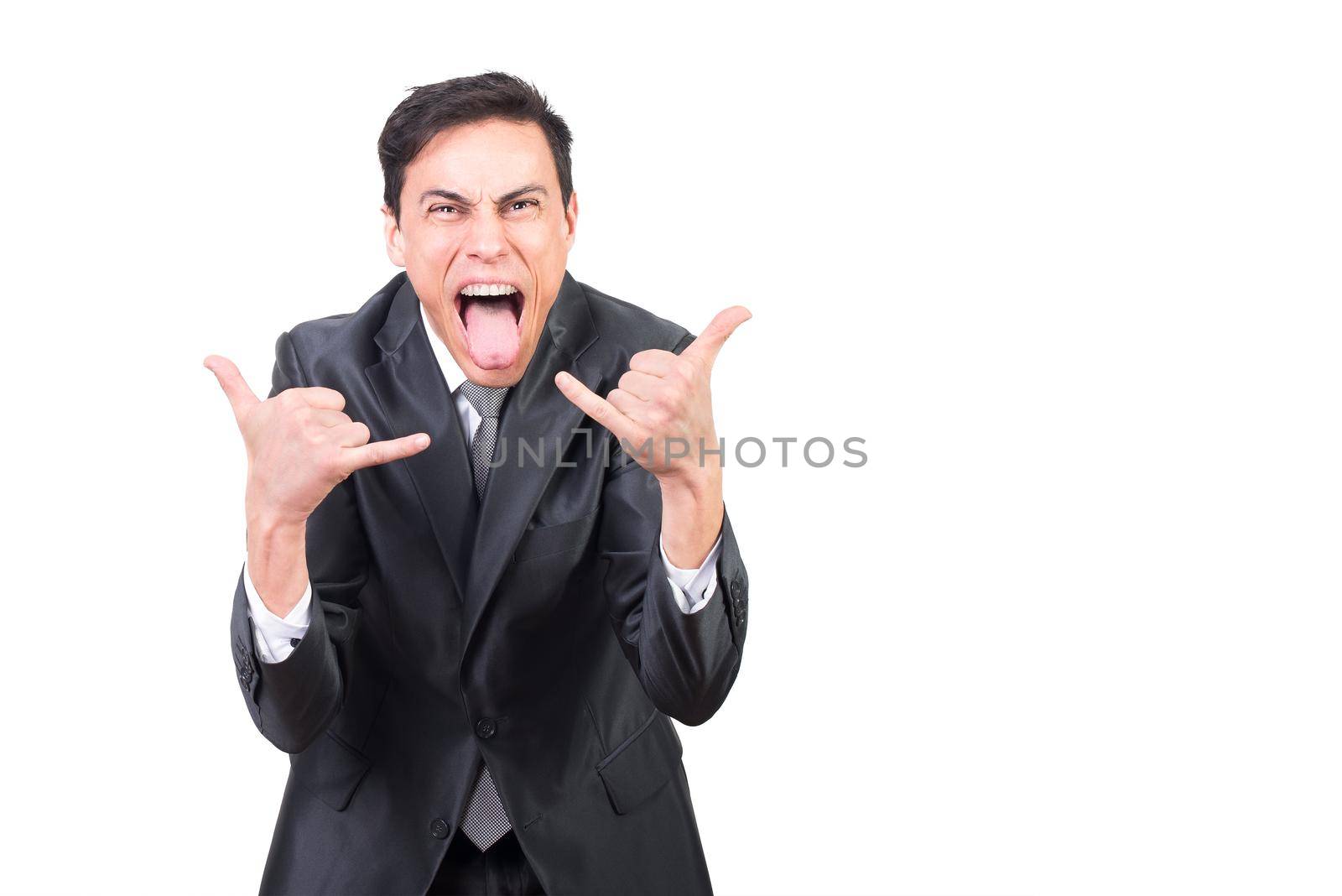 Cheerful adult male with open mouth and tongue out showing rock gesture while standing against white background and looking at camera