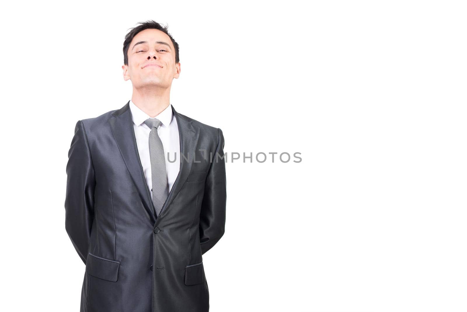 Successful male in elegant suit looking at camera with smile while standing with hands behind back isolated on white background