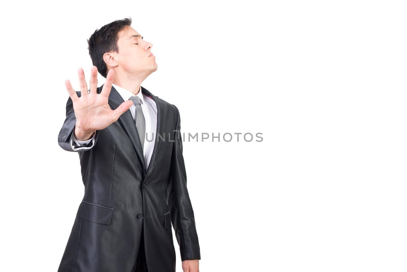 Dissatisfied male executive worker closing eyes and showing rejection gesture against white background in studio