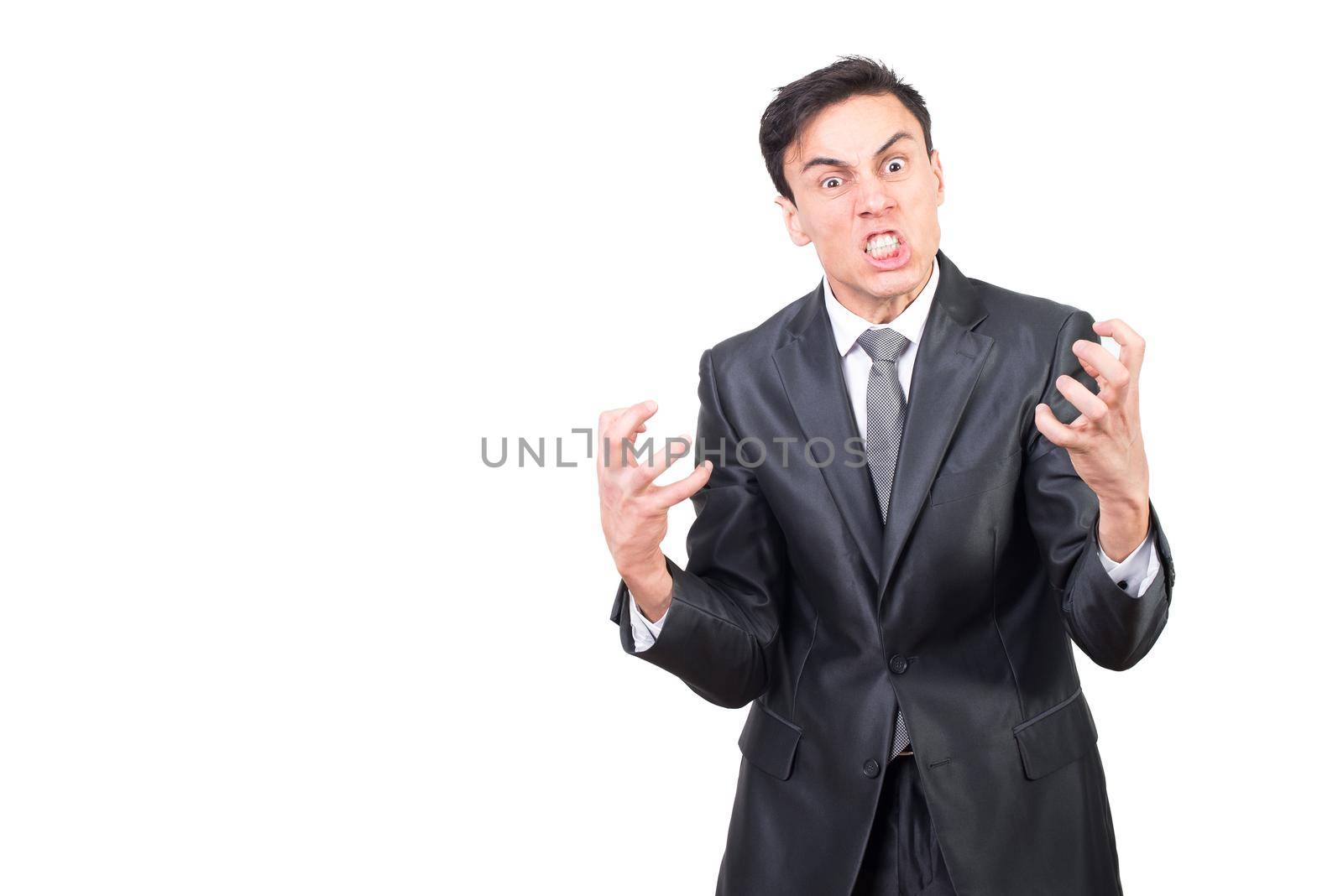 Furious and angry male in formal suit clenching teeth in rage and looking at camera with eyes wide open against white background
