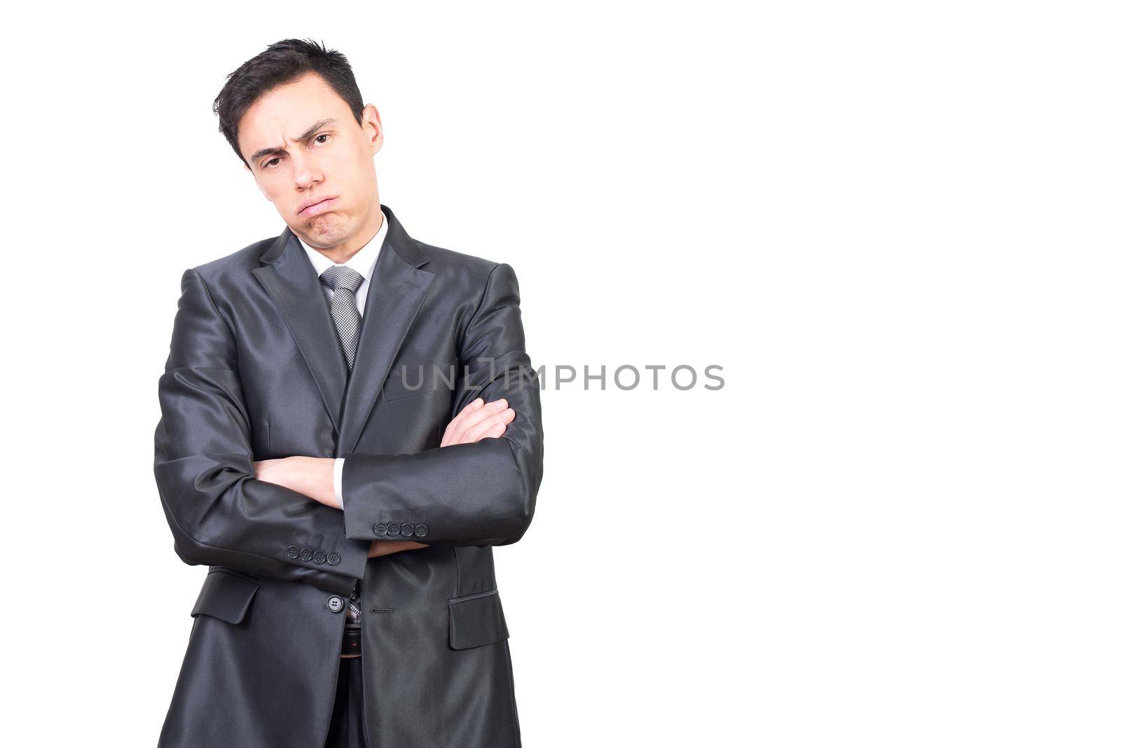 Overworked bored young male manager with dark hair in formal outfit exhaling and looking at camera while standing against white background with crossed arms