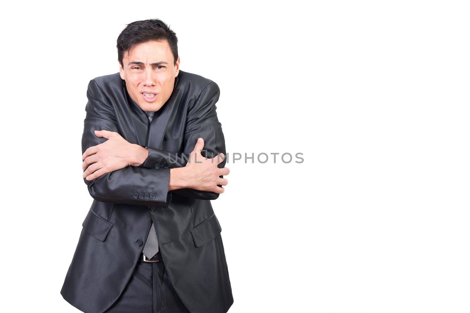 Male in formal suit embracing himself for warming while feeling cold in studio isolated on white background