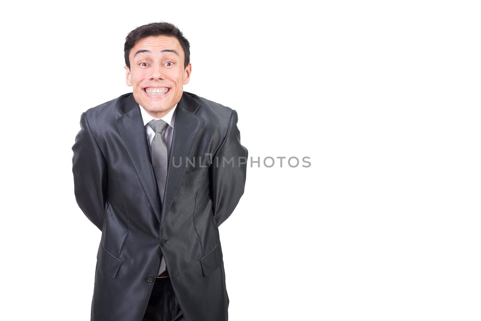 Pleased male in elegant outfit looking at camera with smile and hands behind back while standing isolated on white background in studio