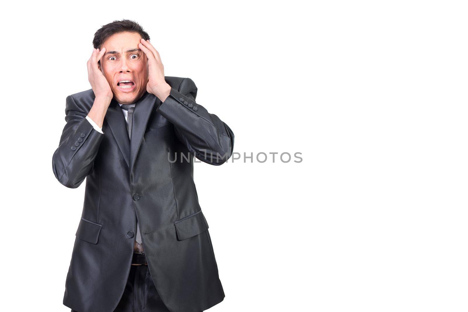 Shocked young male entrepreneur with dark hair in formal outfit gabbing head and looking at camera with scared grimace against white background