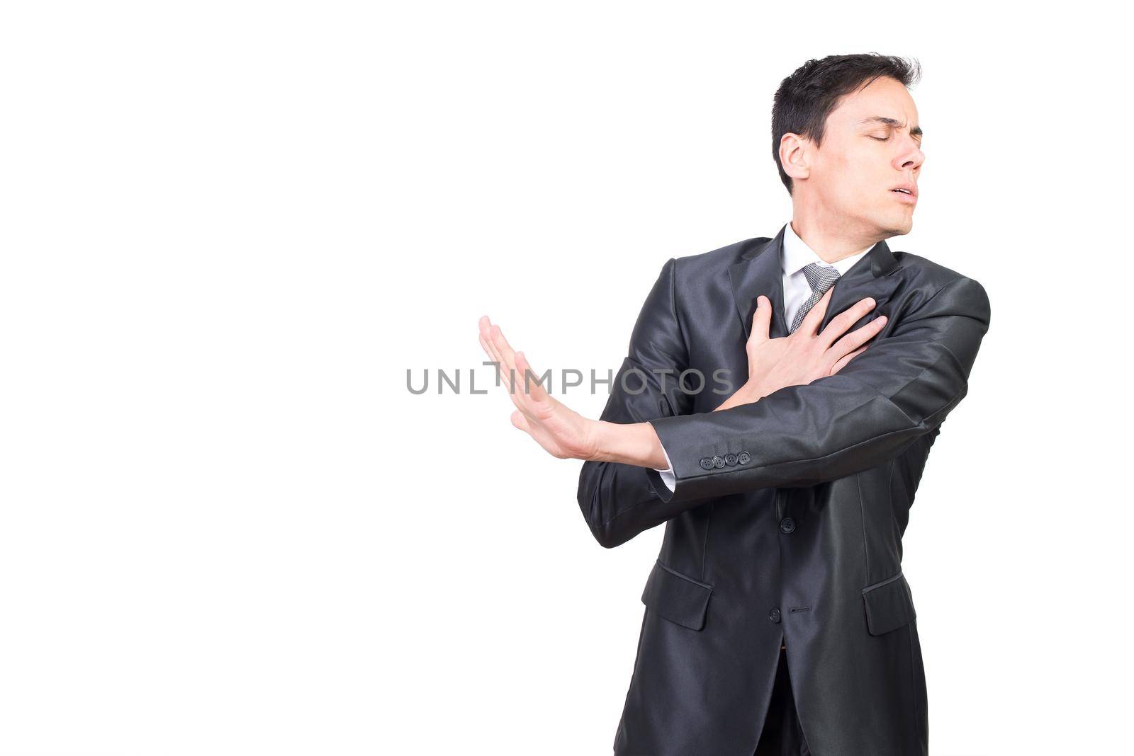 Harmed man in formal suit touching chest with hand while standing with closed eyes isolated on white background in studio