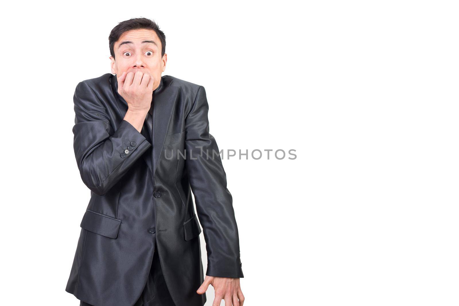 Anxious male in elegant suit covering mouth with hand and looking at camera while standing isolated on white background in studio