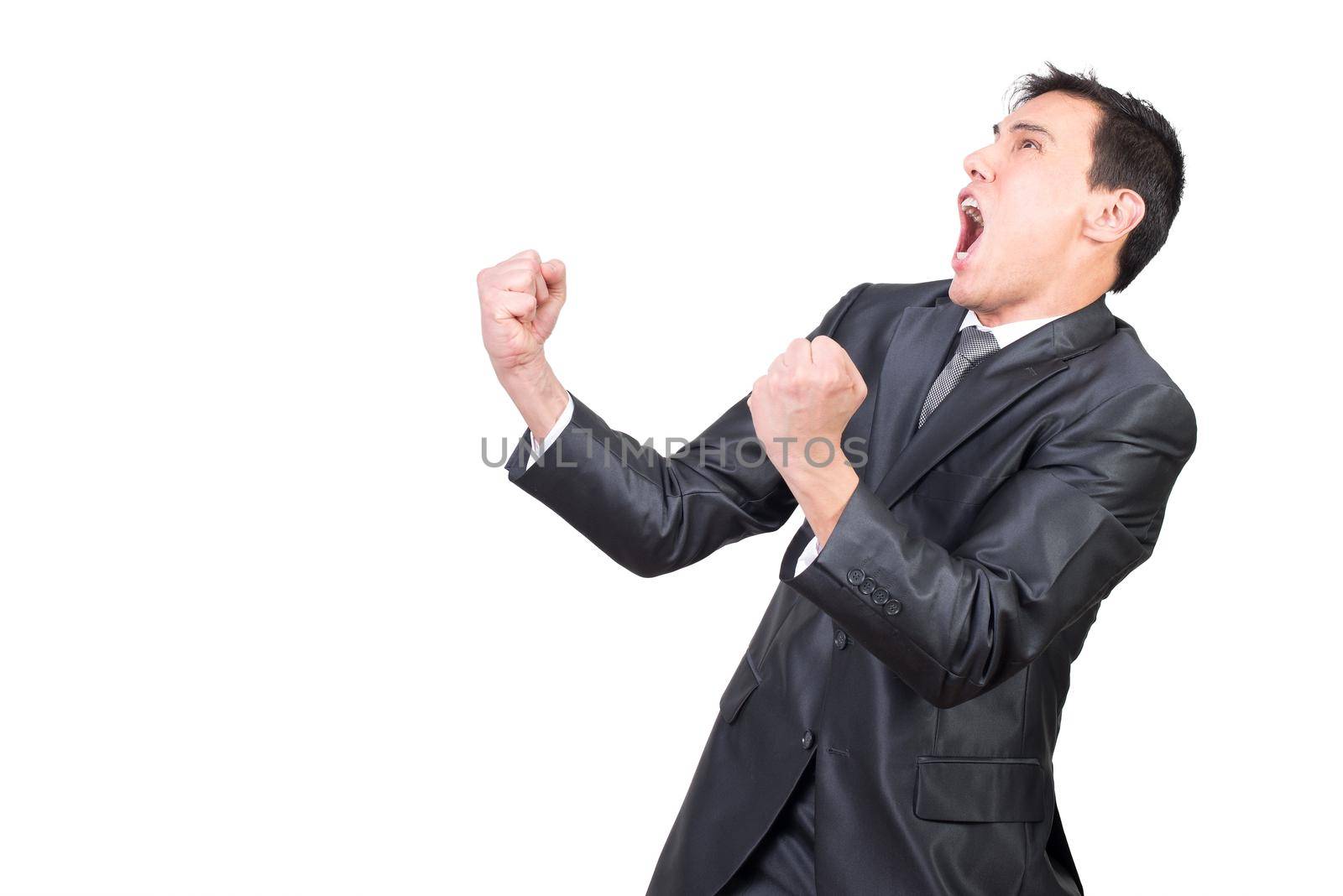 Delighted expressive young male manager with dark hair in formal outfit clenching fists and screaming happily while celebrating achievement against white background