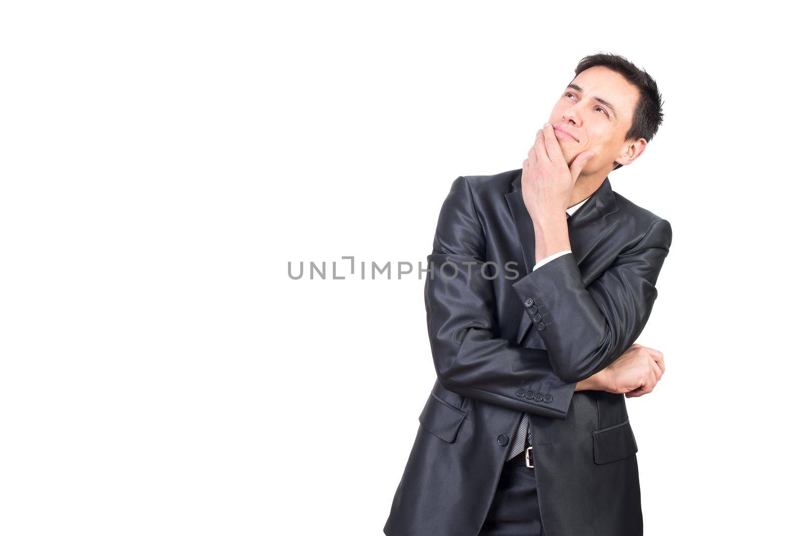 Content male in elegant suit touching chin and looking up with dreamy face expression while standing isolated on white background