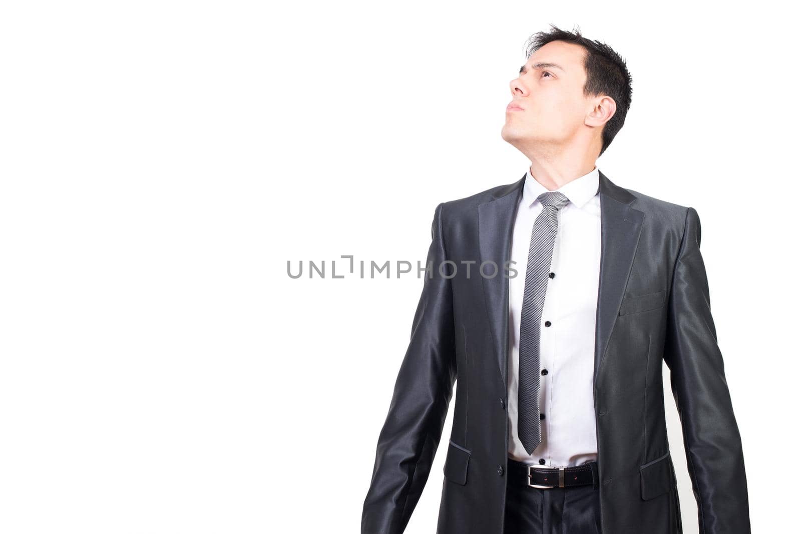 Dignified young male entrepreneur with dark hair in elegant suit and tie looking away with confidence against white background