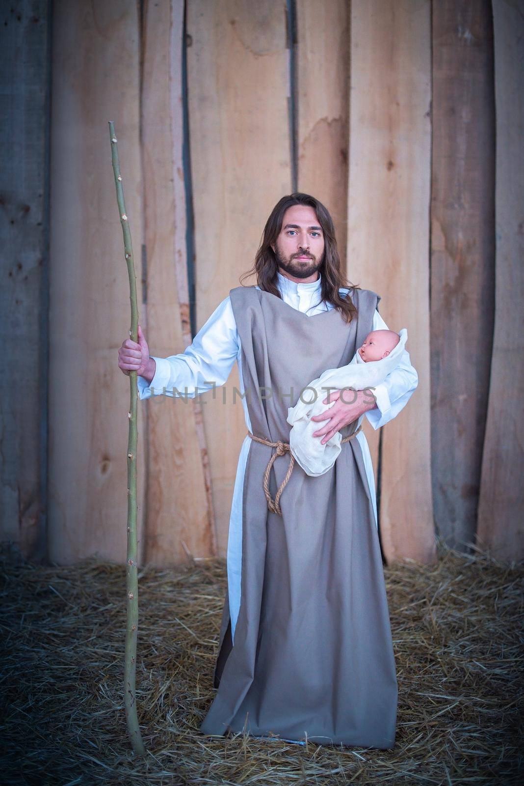 Vertical portrait of the figure of Joseph holding Jesus baby in a lgtb nativity scene