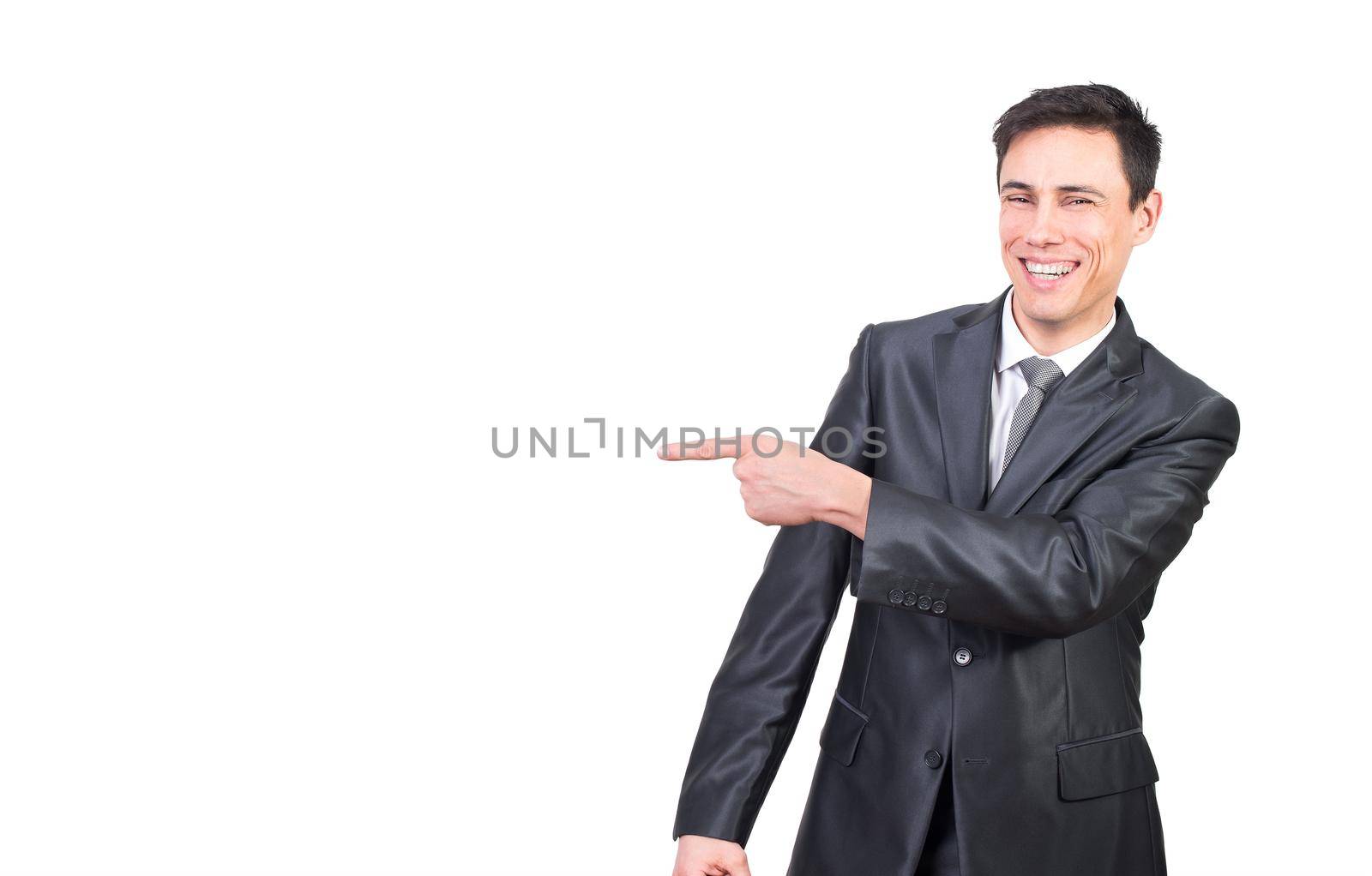 Happy smiling male leader in formal suit pointing aside with finger and looking at camera against white background