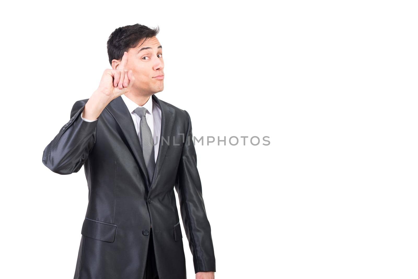 Intelligent male in elegant suit pointing up and looking at camera while standing isolated on white background in light studio
