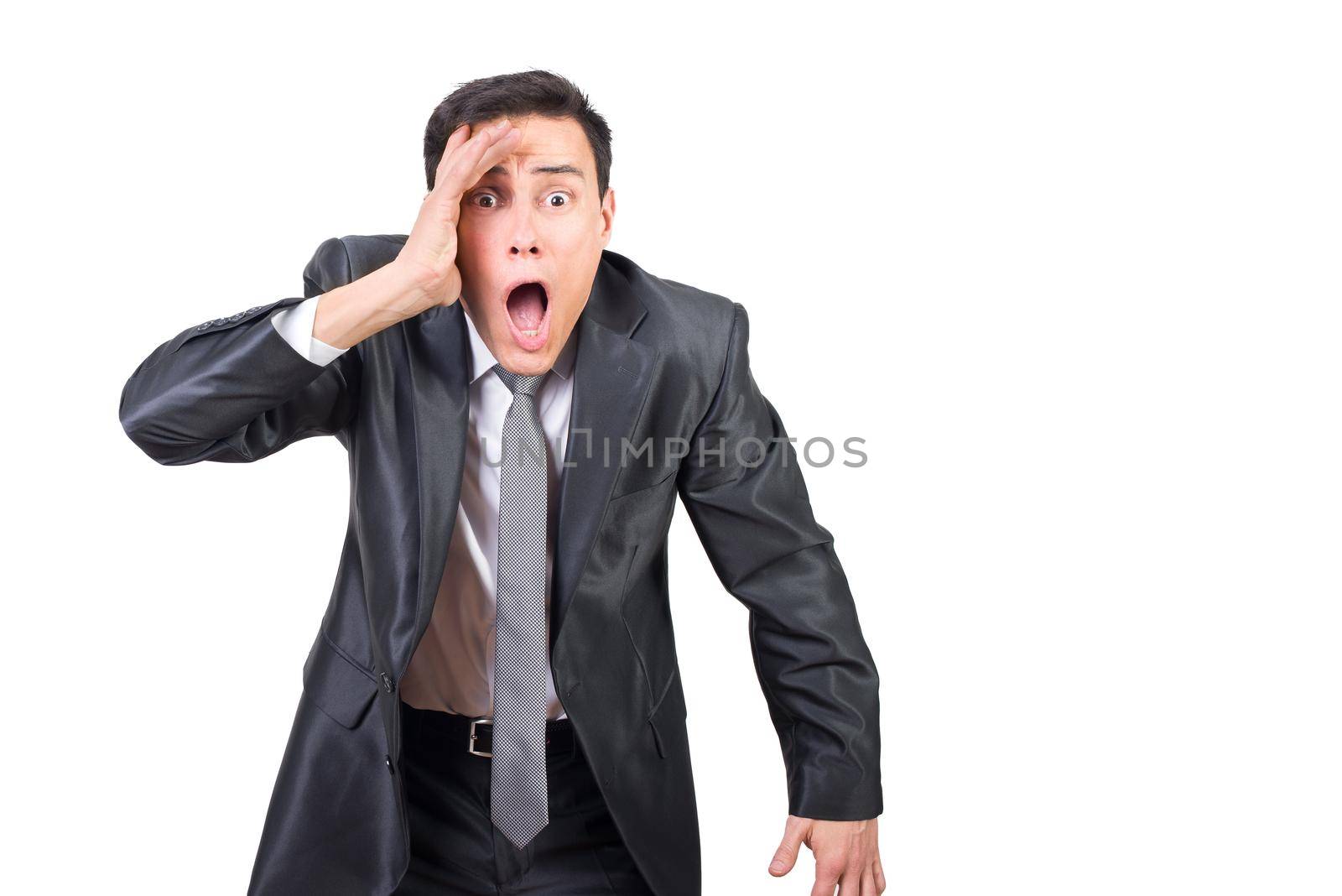 Astonished male entrepreneur in formal outfit touching face and looking at camera while standing isolated on white background in studio