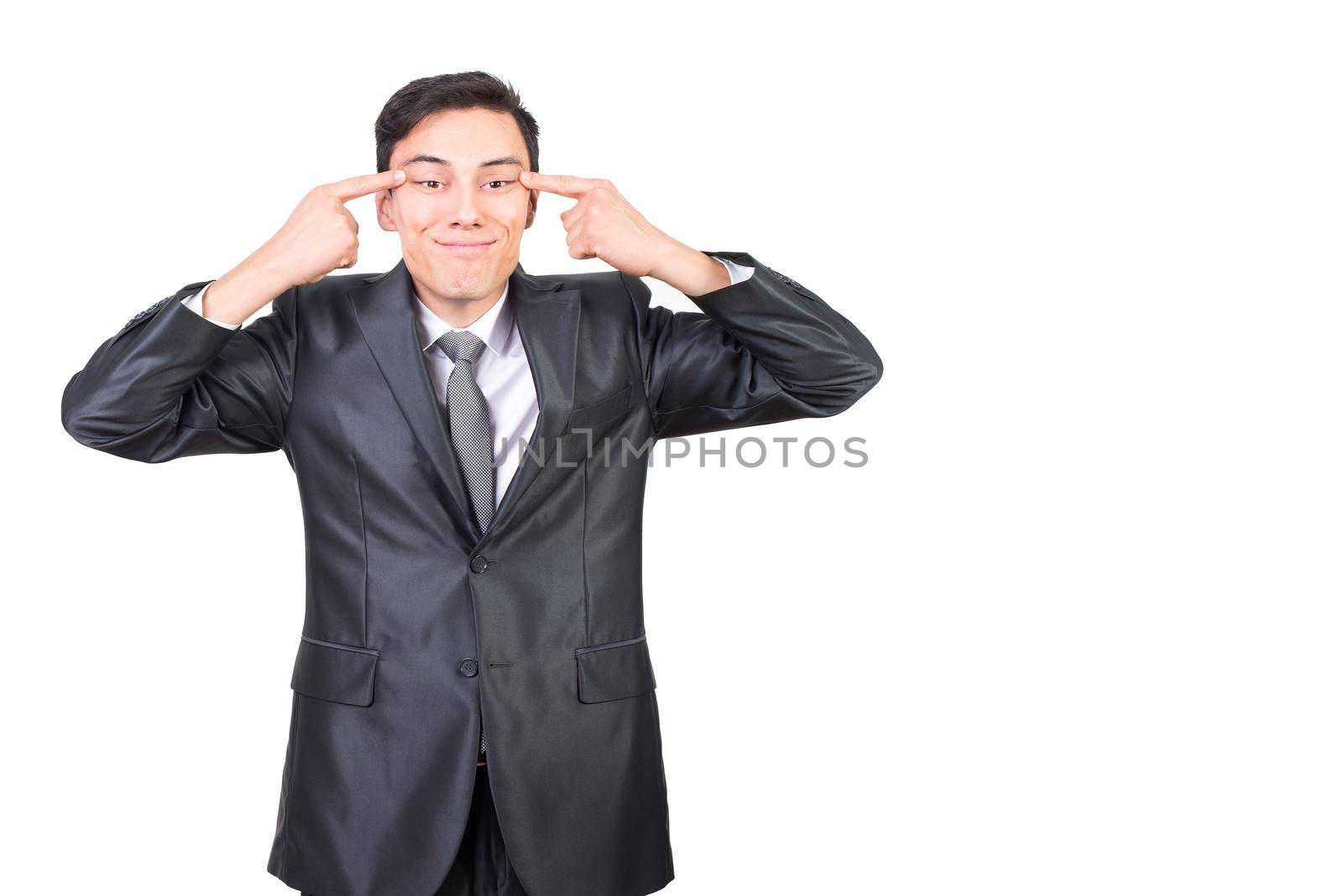 Confident male in classy costume touching and stretching skin imitating Chinese eye sections standing against white background