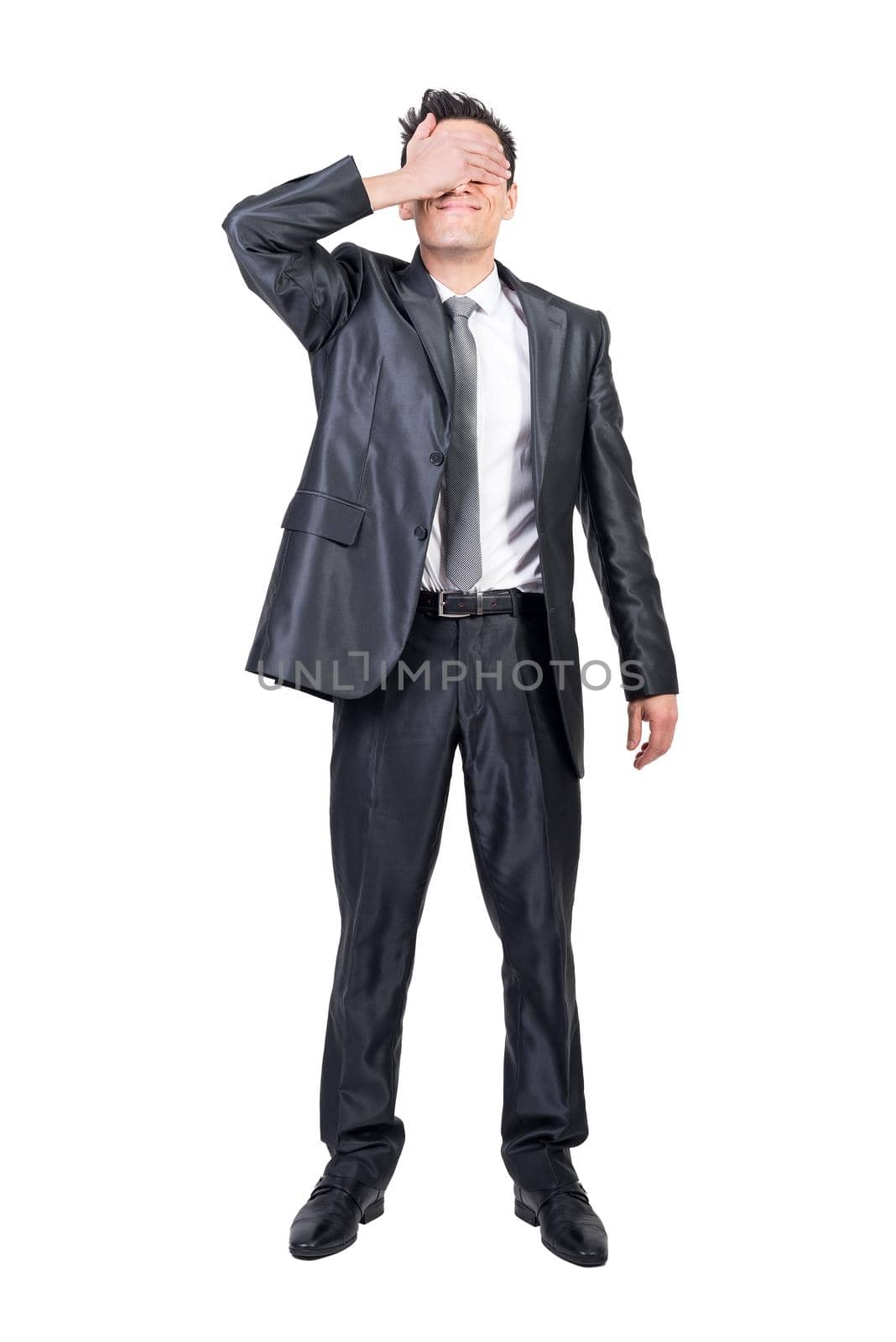 Full body of content male entrepreneur in suit covering eyes while standing on white isolated background in studio