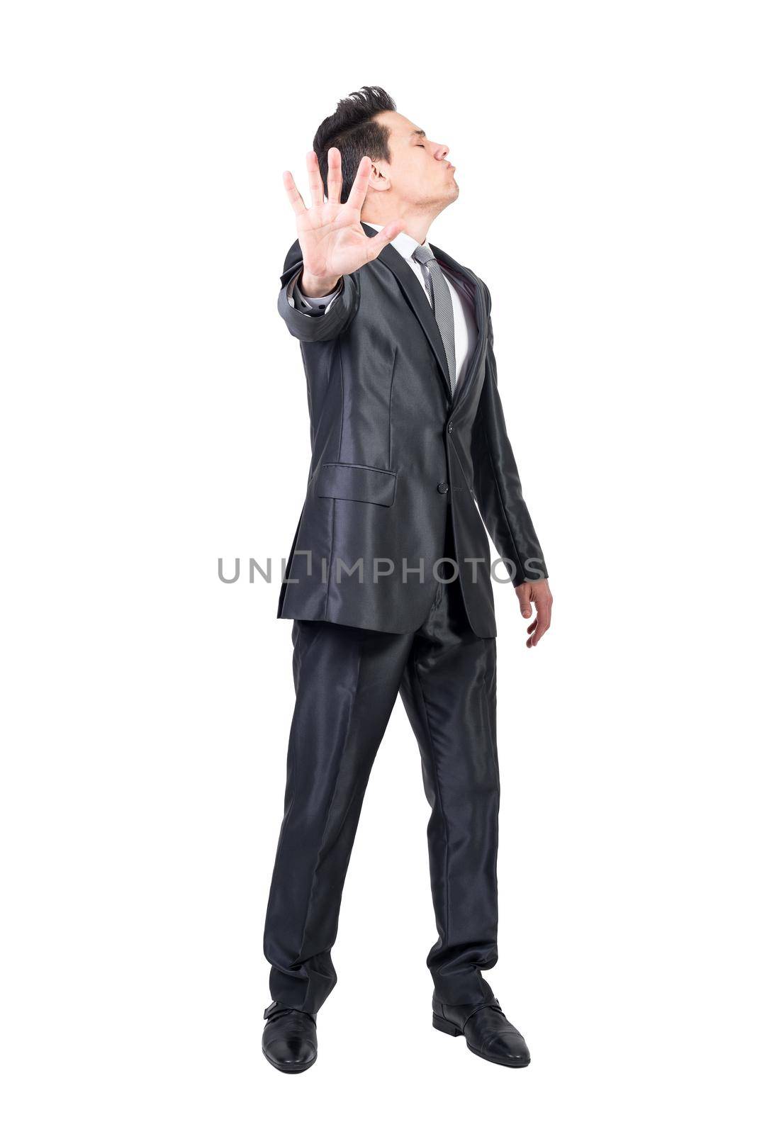 Full body of funny offended male entrepreneur in formal suit showing stop sign on white background in studio