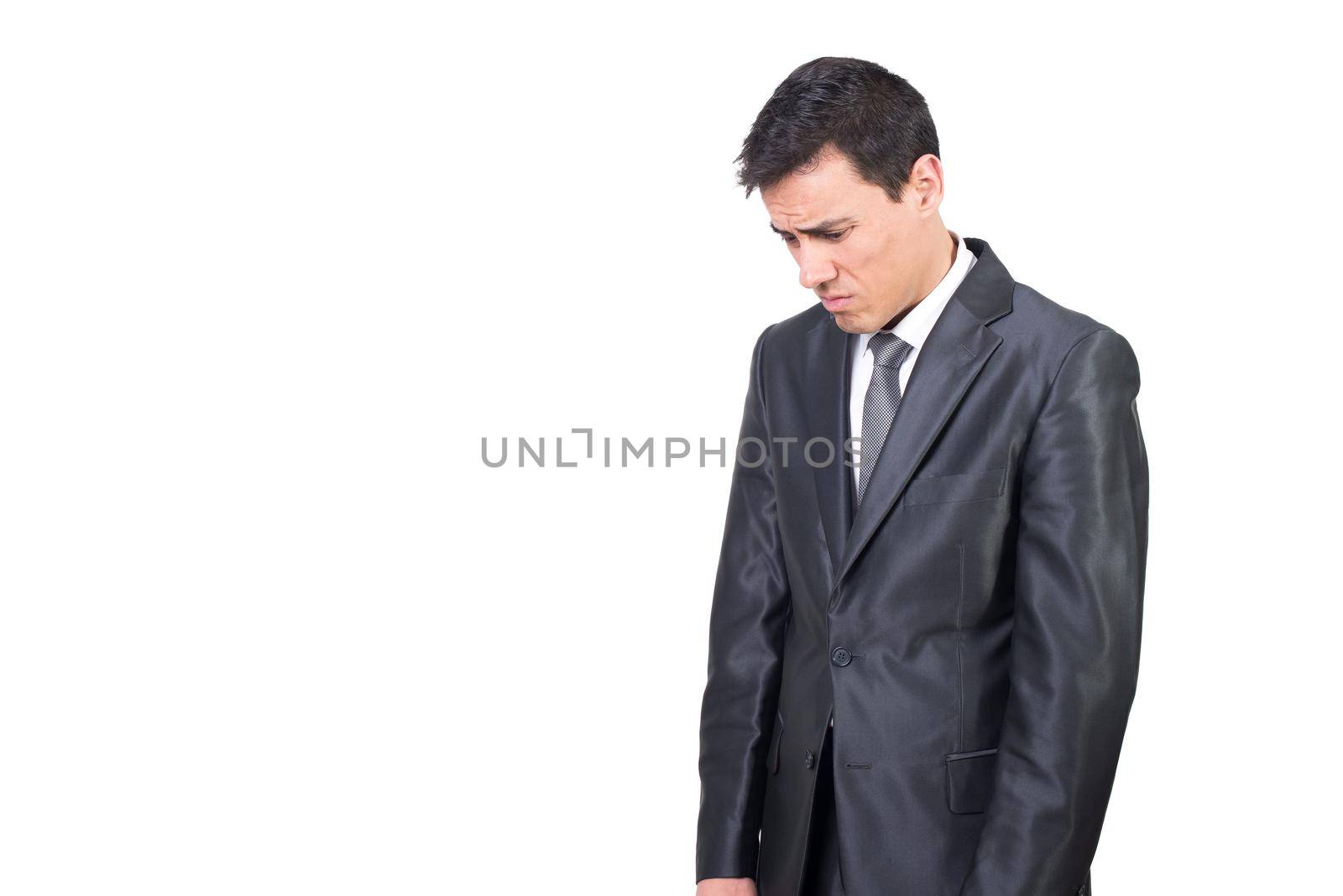 Mid shot of discontent male entrepreneur in formal wear looking down with frustration while standing isolated on white background in studio