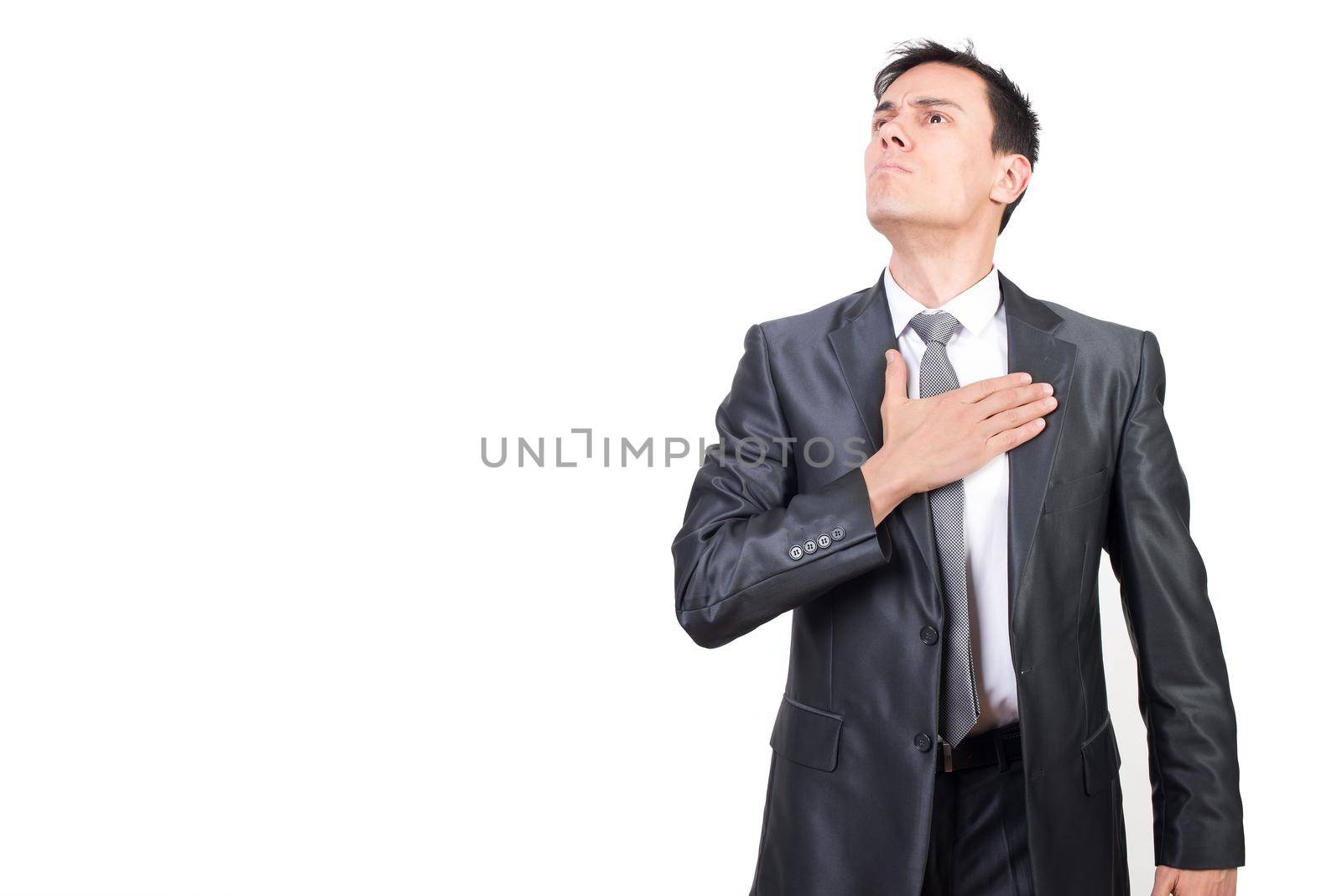 Confident male patriot keeping hand on chest as gesture of responsibility and pledge of allegiance to state while standing in studio against white background