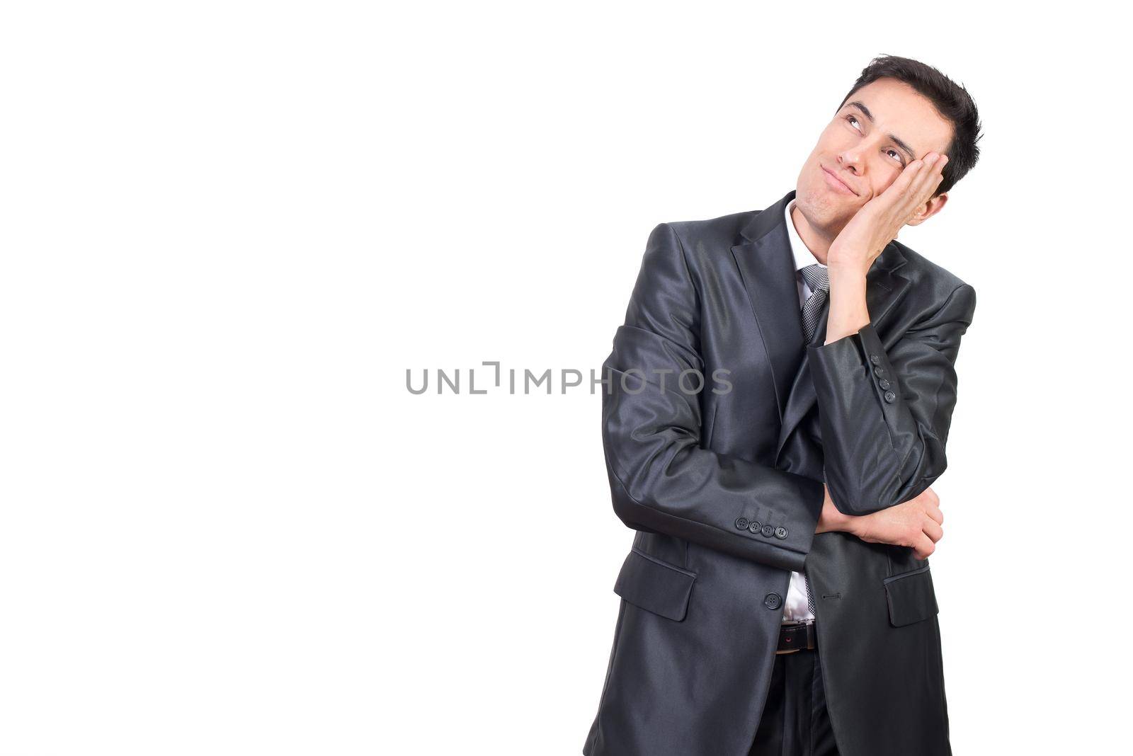 Content male in elegant suit touching cheek and looking up with dreamy face expression isolated on white background in studio