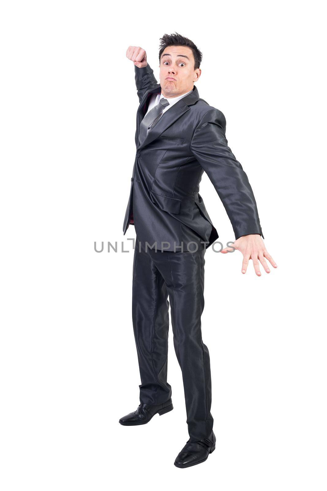 Full body of angry male in elegant suit looking at camera with clenched fist while standing isolated on white background in studio
