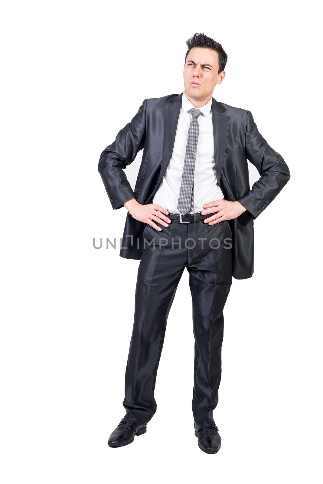 Full body of comic male entrepreneur in suit expressing doubt and looking up while standing with hands on waist against white background