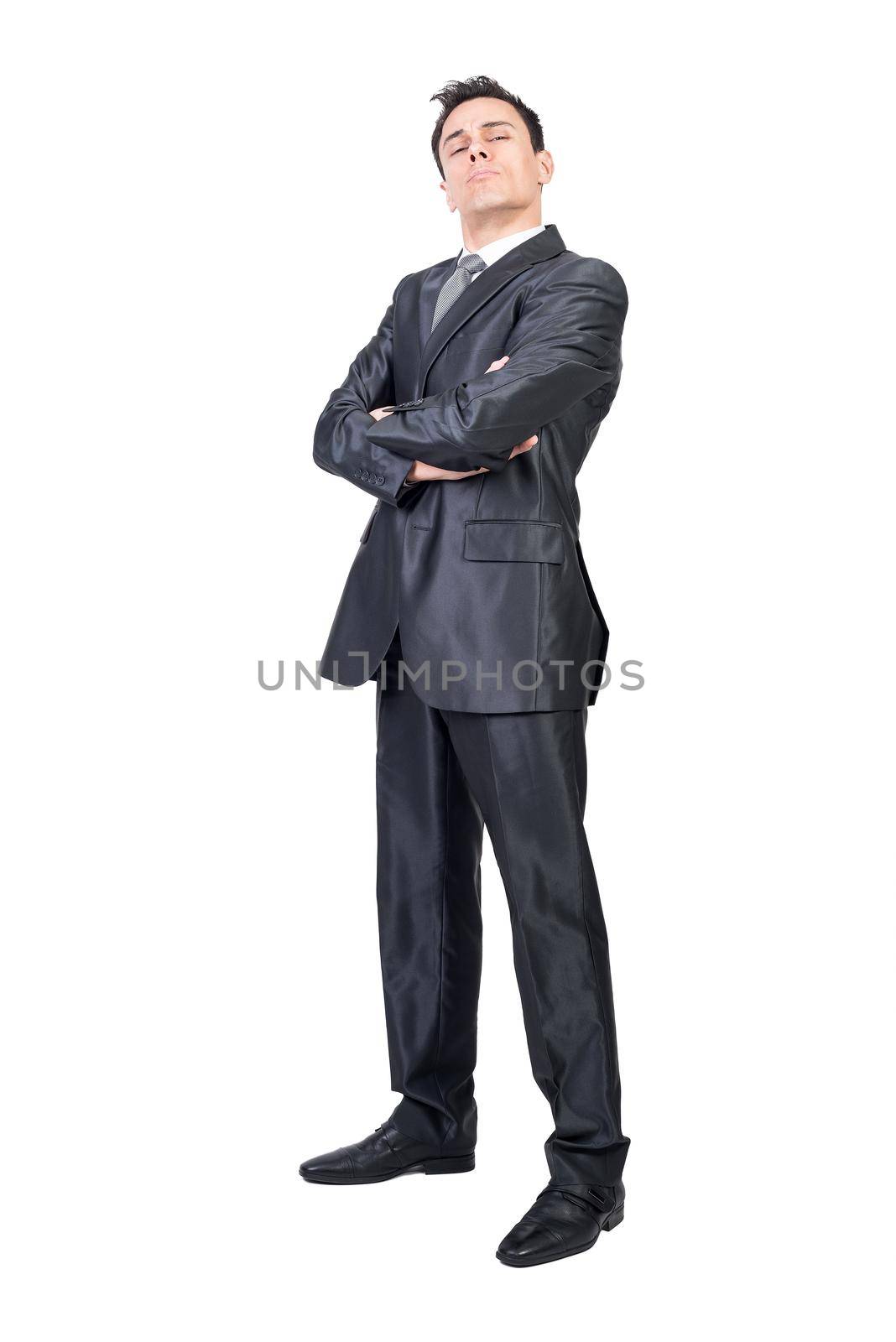 Full body of reliable self assured businessman in formal suit standing with hands folded and looking at camera with arrogance