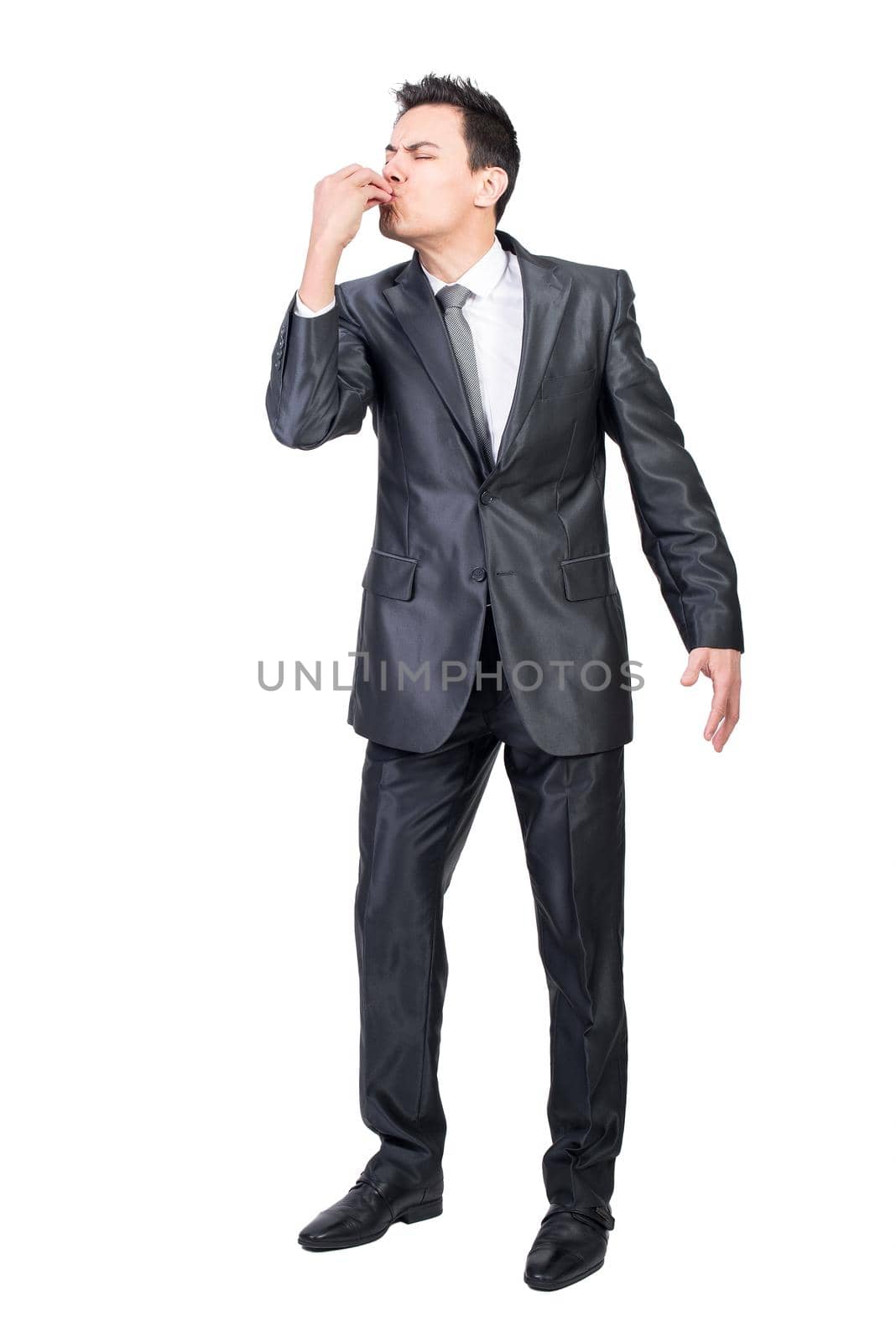 Full body of businessman with closed eyes kissing fingers while making delicious gesture in studio against white background