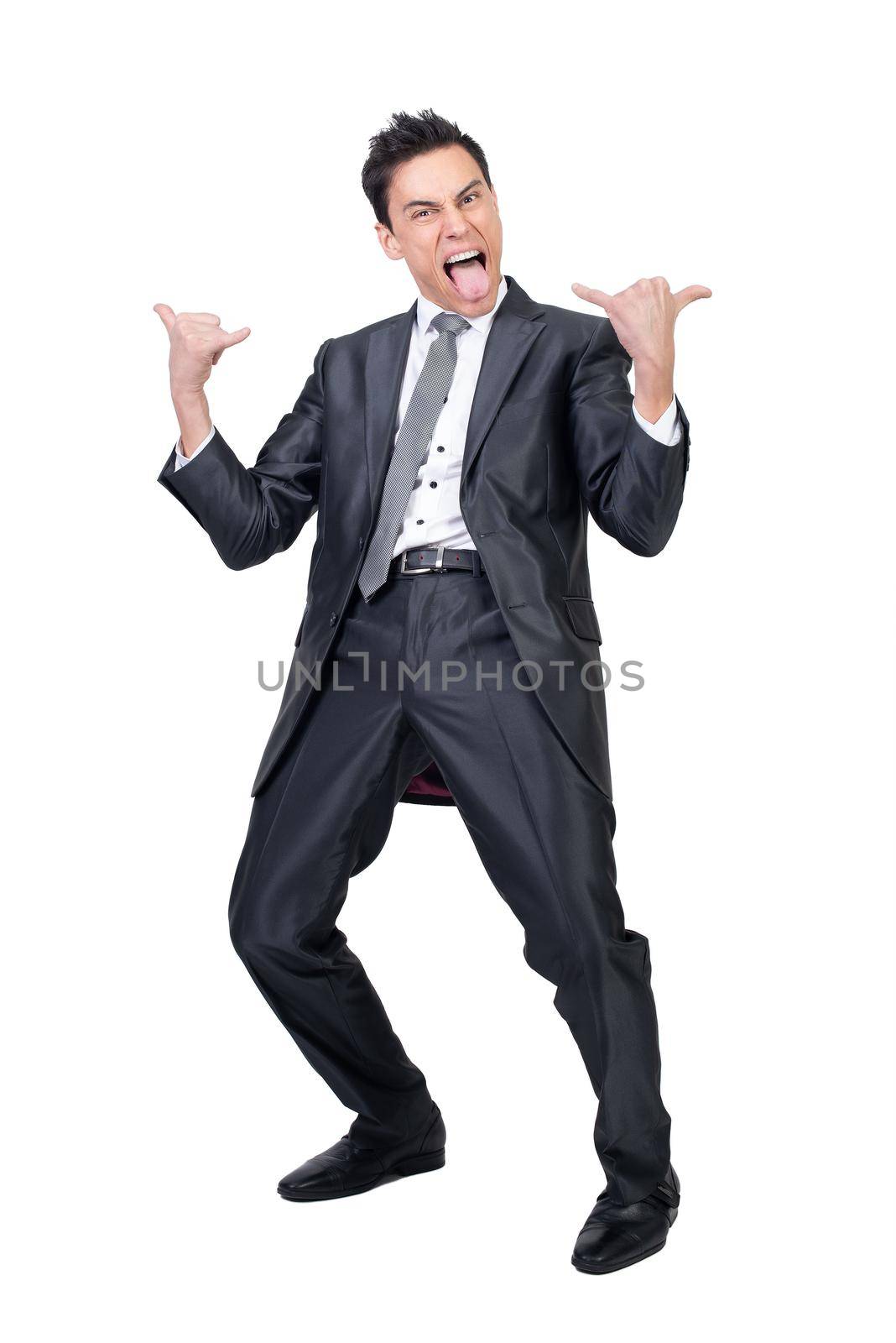 Full body of expressive male in formal suit showing horn gesture and screaming with opened mouth and tongue out in studio against white background